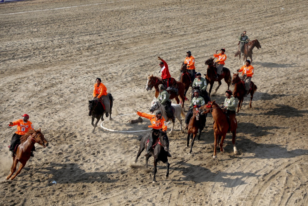 This photograph taken on March 8, 2024 shows Afghan riders of the Yama Petroleum (orange) and Baghlan teams competing at the Buzkashi league tournament final in Mazar-i- Sharif
