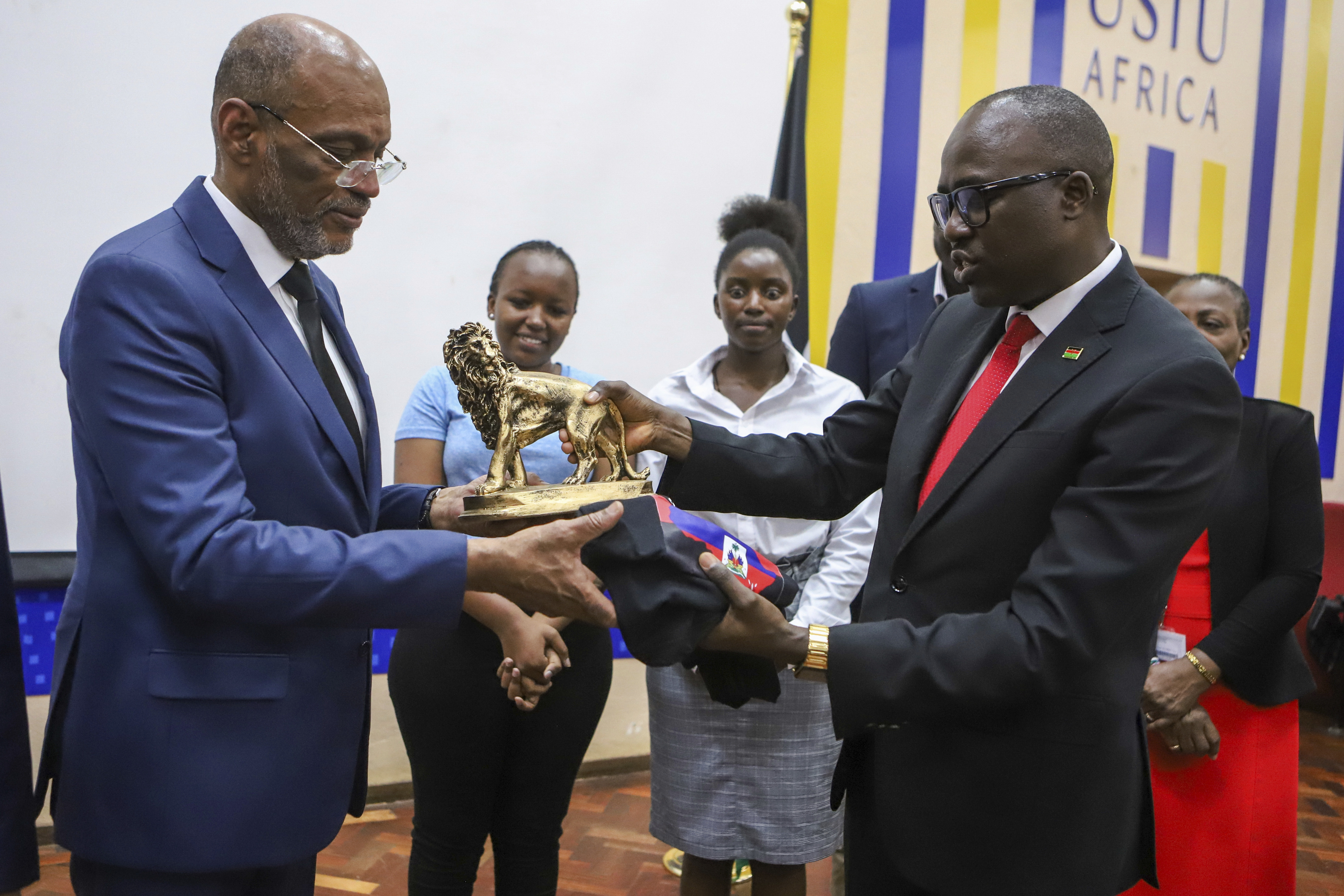 Ariel Henry accepting a statue of a golden lion as a gift from Kenya's foreign minister
