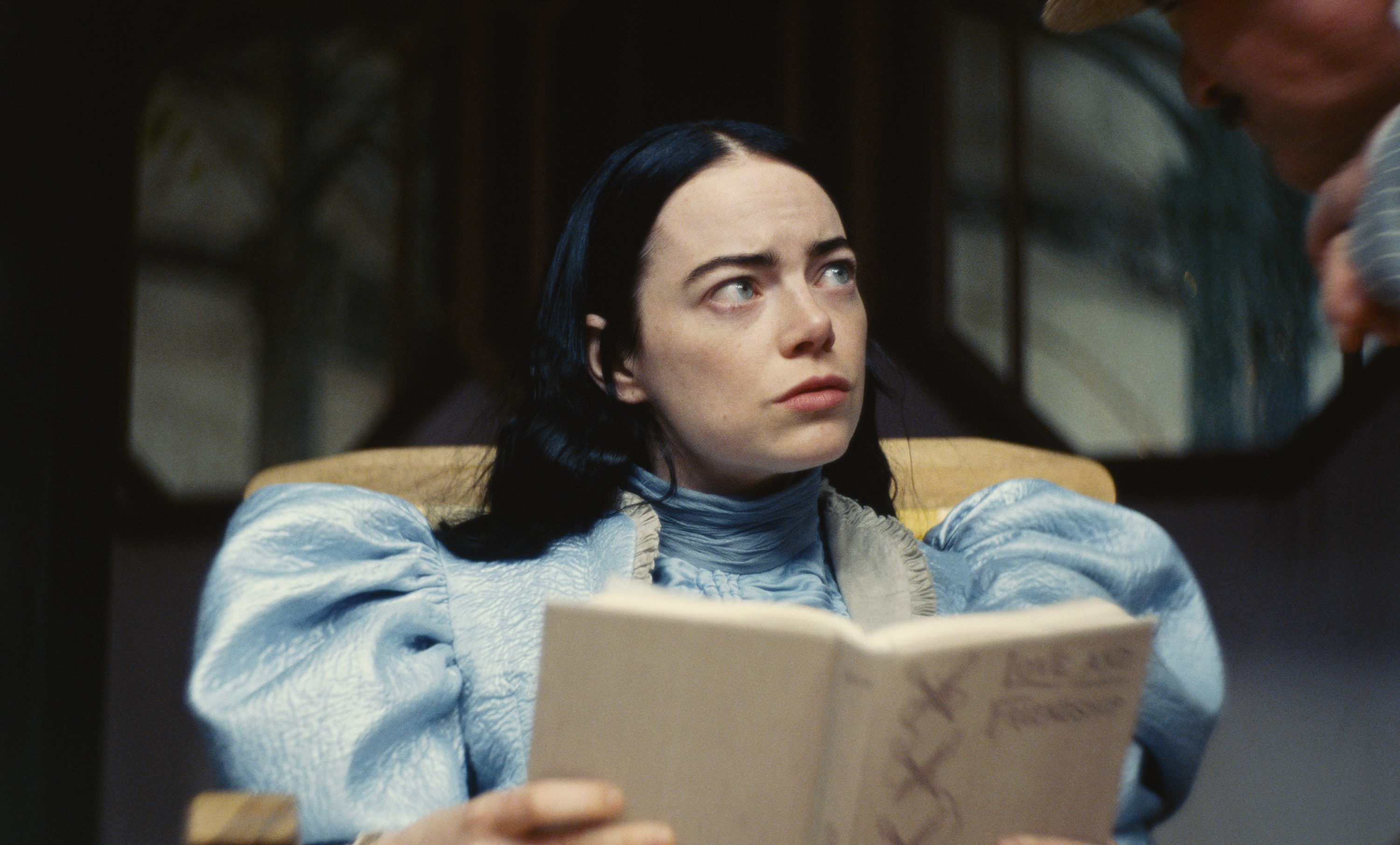 Emma Stone in Poor Things, reading a book