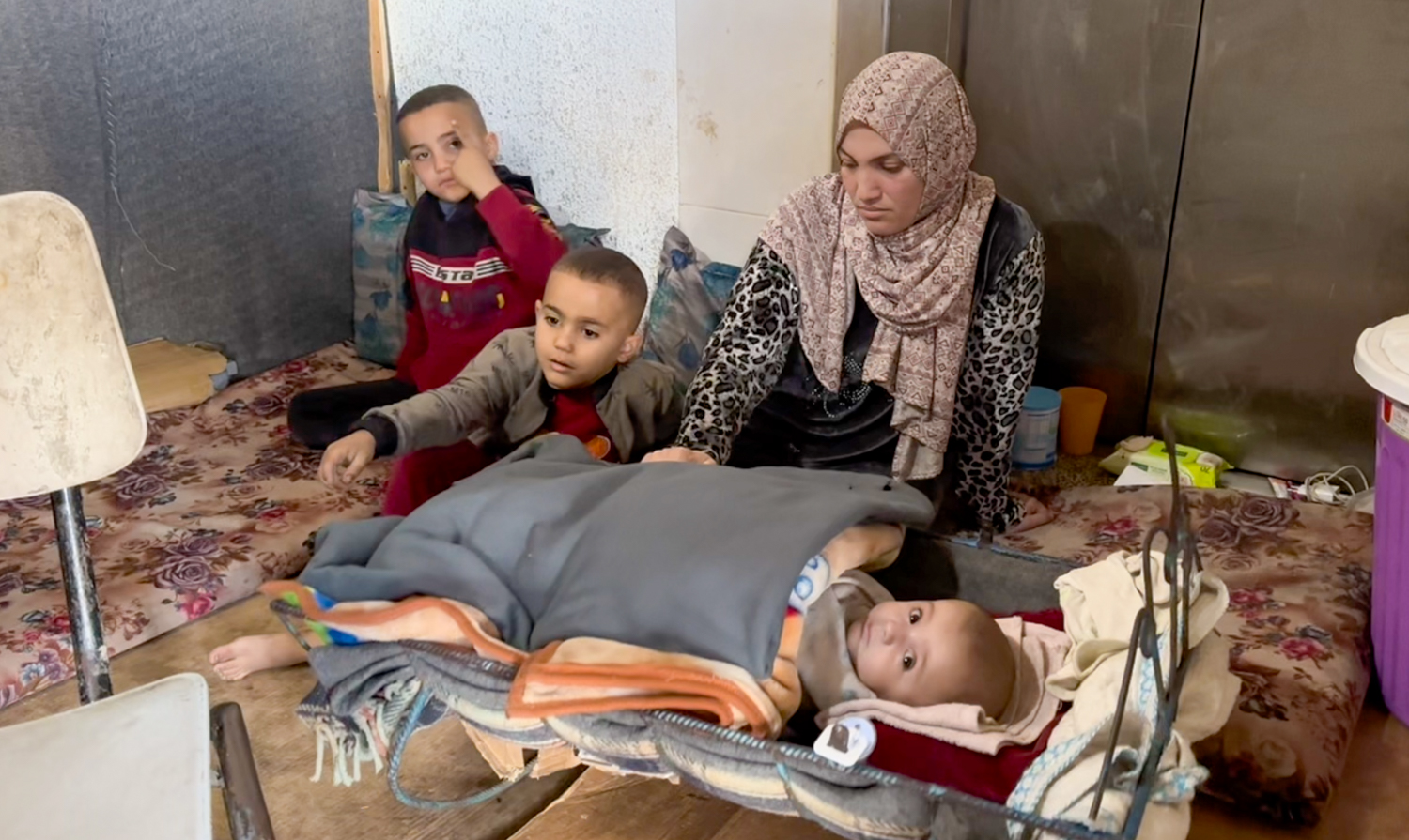 Yazan's mother and siblings crouched on the floor in their shelter