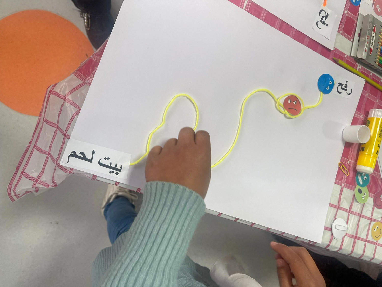 look over the shoulder of another little girl putting together her art piece