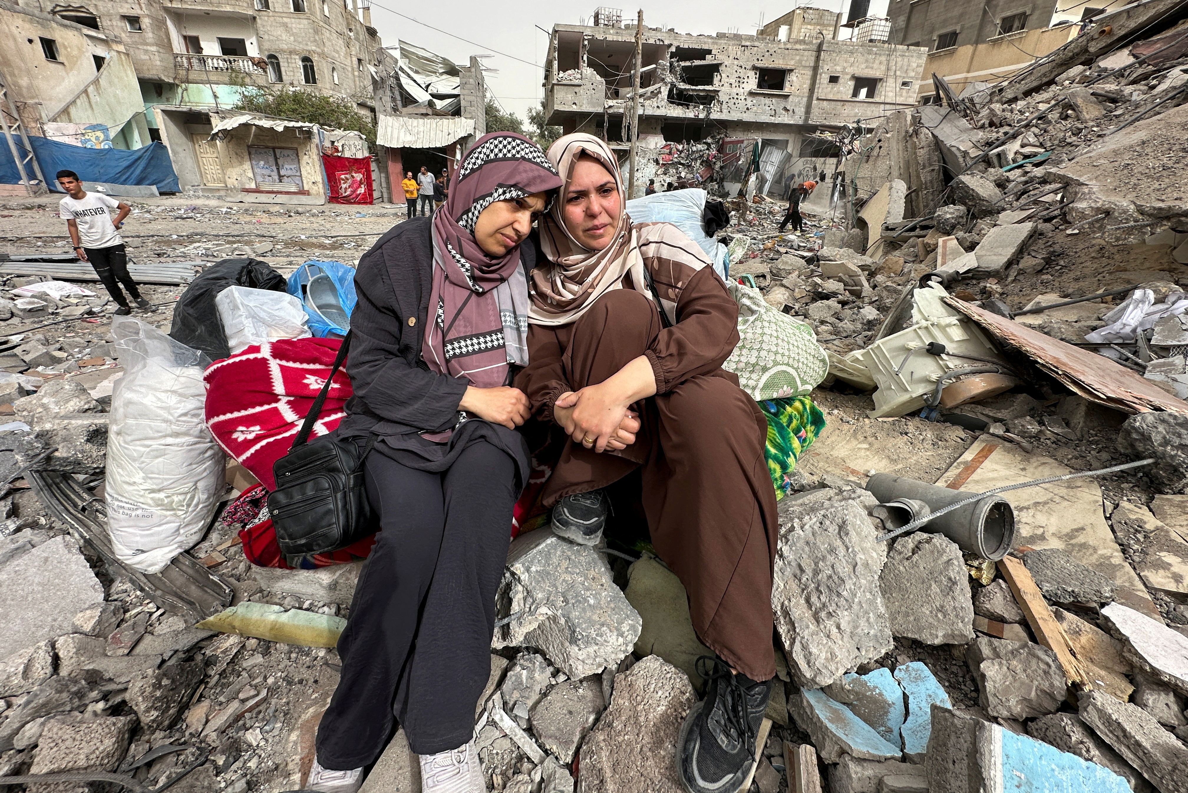 Palestinian women sit on the rubble of a residential building where they used to live after an Israeli raid in Nuseirat in the central Gaza Strip
