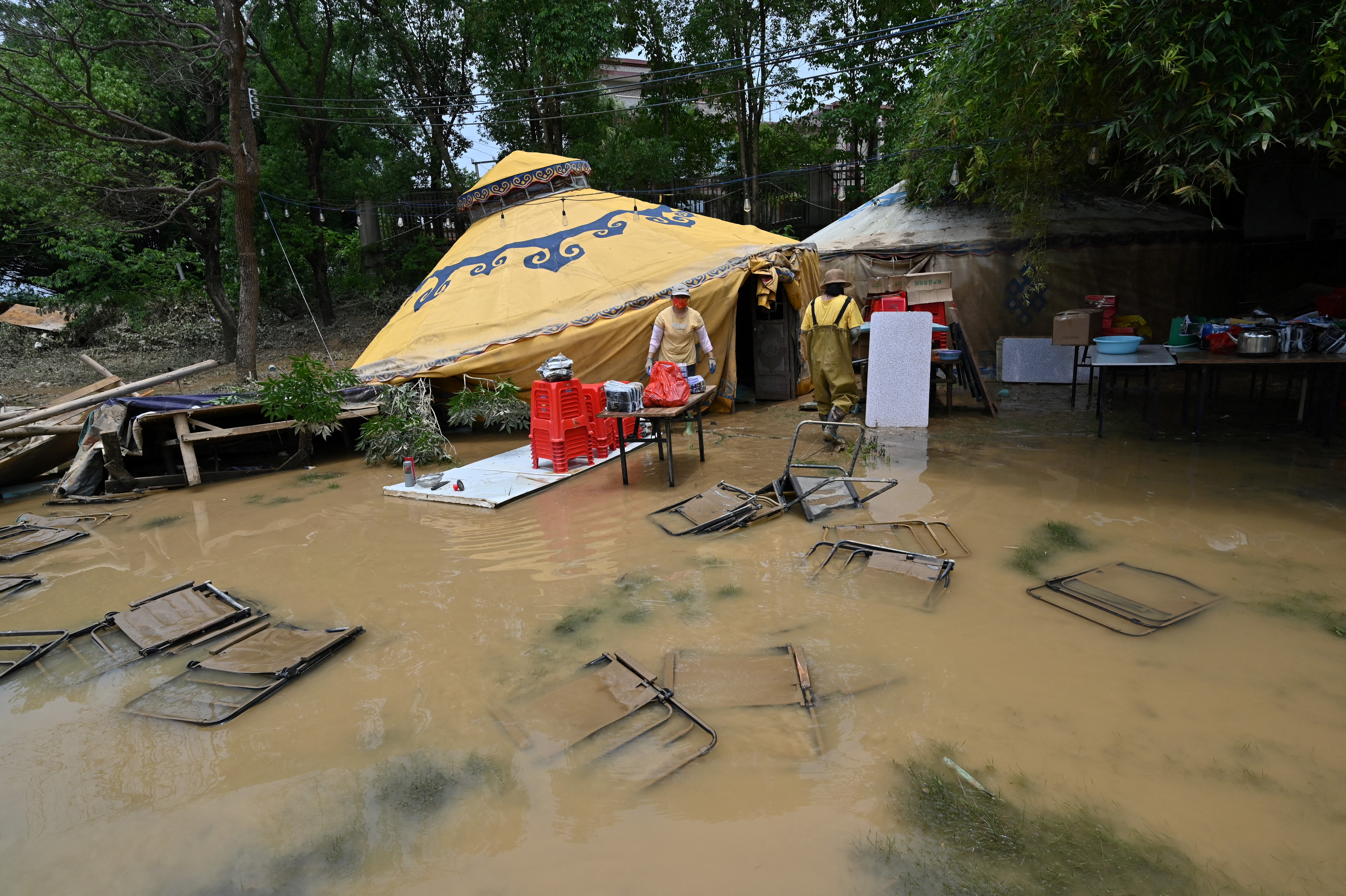 Chairs are submerged as workers collect items after torrential rains flooded the area in Shatang village, in Qingyuan, in northern Guangdong province on April 24