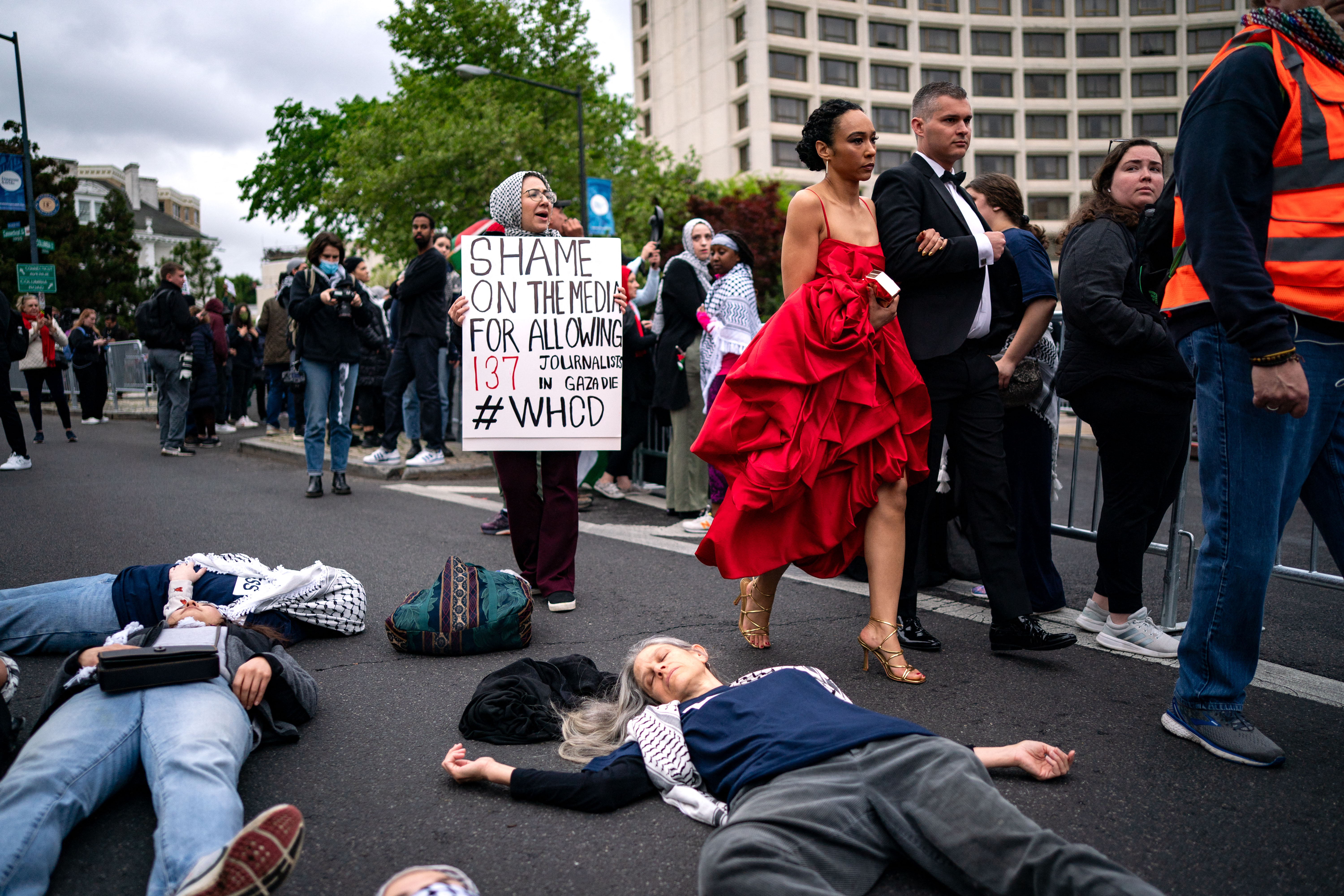 people walk past a sign saying shame on the media
