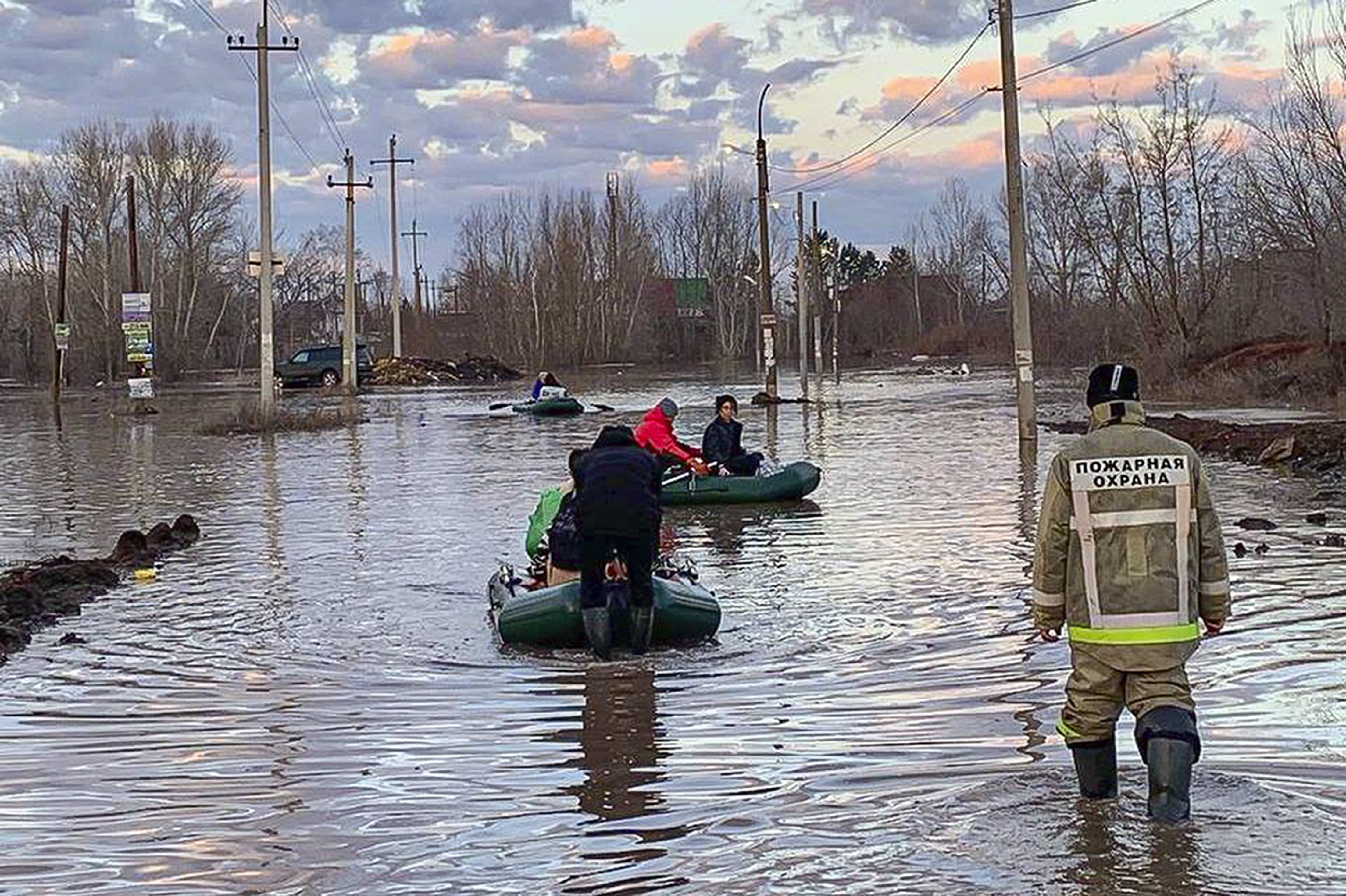 In this photo taken and released by the Administration of the city of Orenburg telegram channel on Friday, April 5, 2024, people use boats while evacuating after a part of a dam burst causing flooding, in Orsk, Russia. 