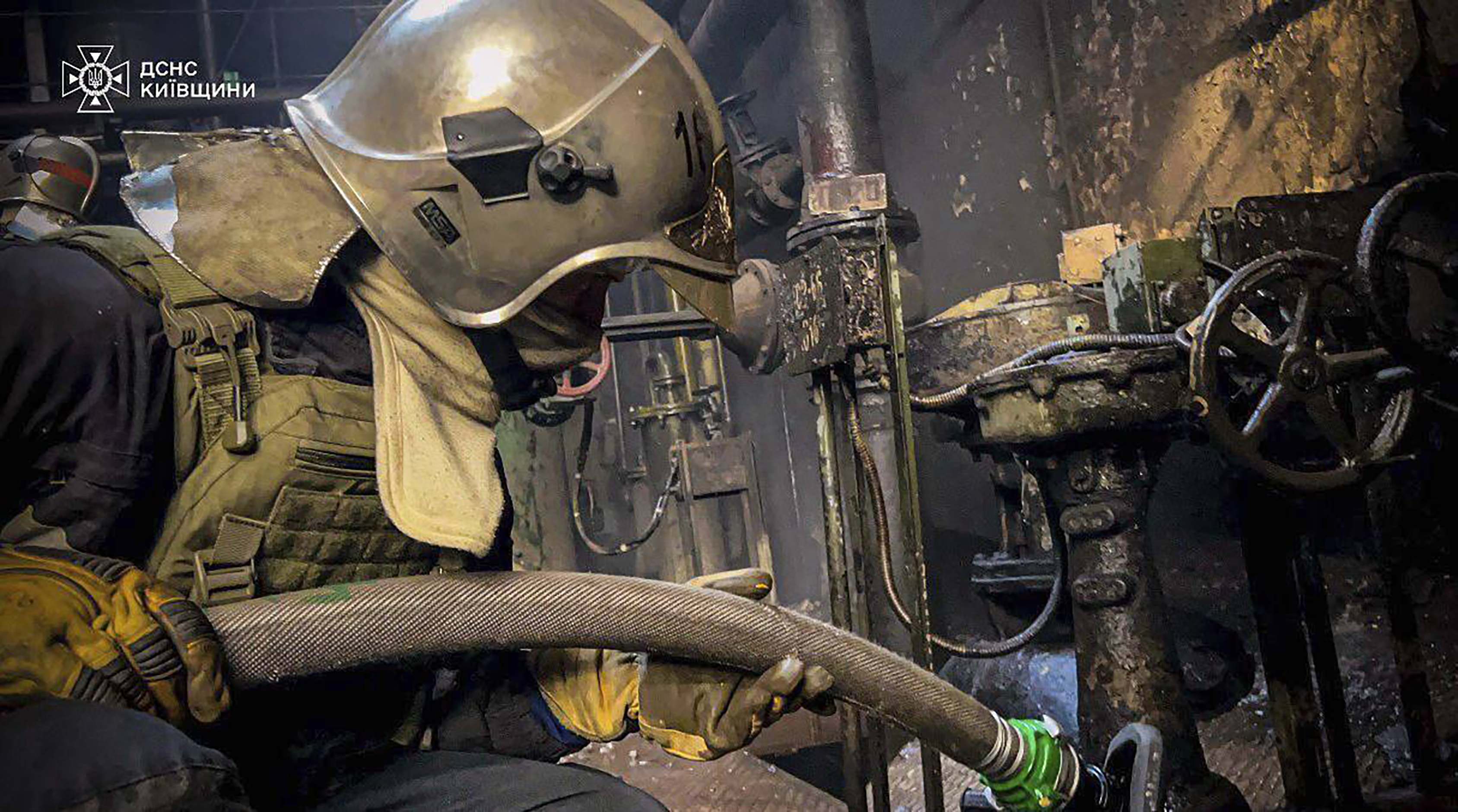 an emergency worker extinguishes a fire after a Russian attack on the Trypilska thermal power plant in Kyiv region, April 11, 2024