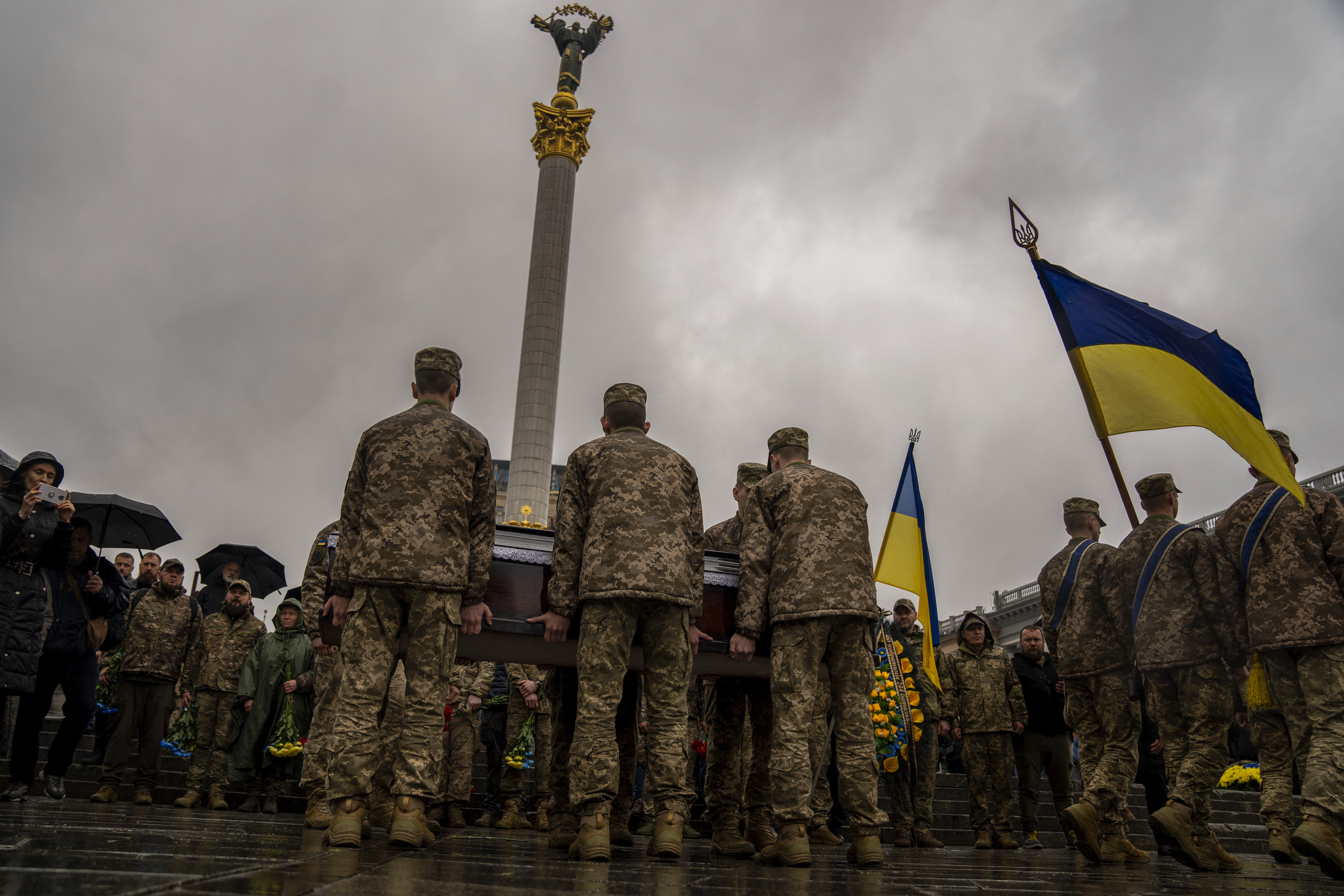 Ukrainian soldiers carrying the coffin of an army paramedic was who was killed in action. One of the mourners is carrying a Ukrainian flag.