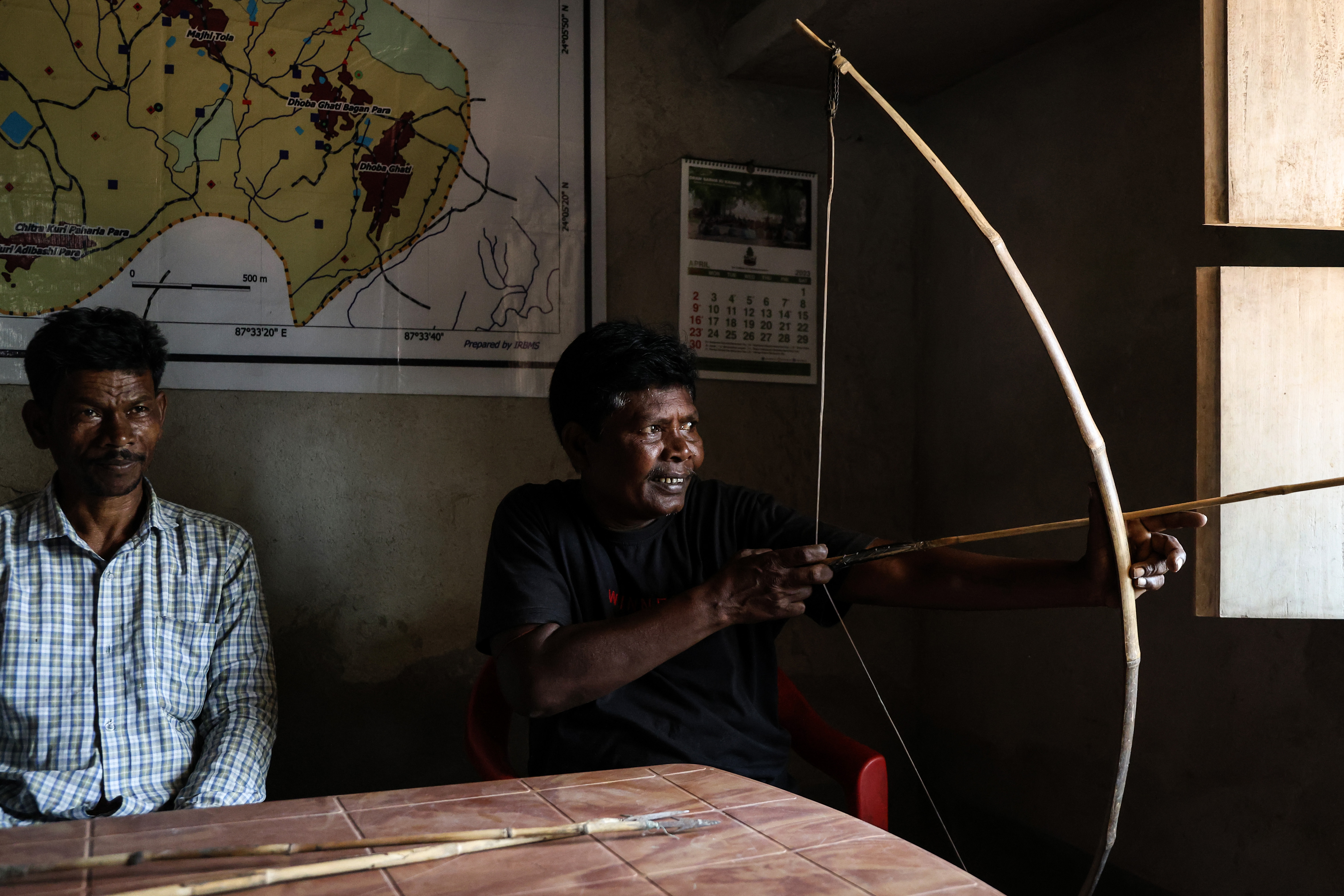 Mangal Murmu holds a bow and arrow to display how Adivasi people drove the Deucha Pachami coal mine’s owners away from their land in Hirapur, Jharkhand