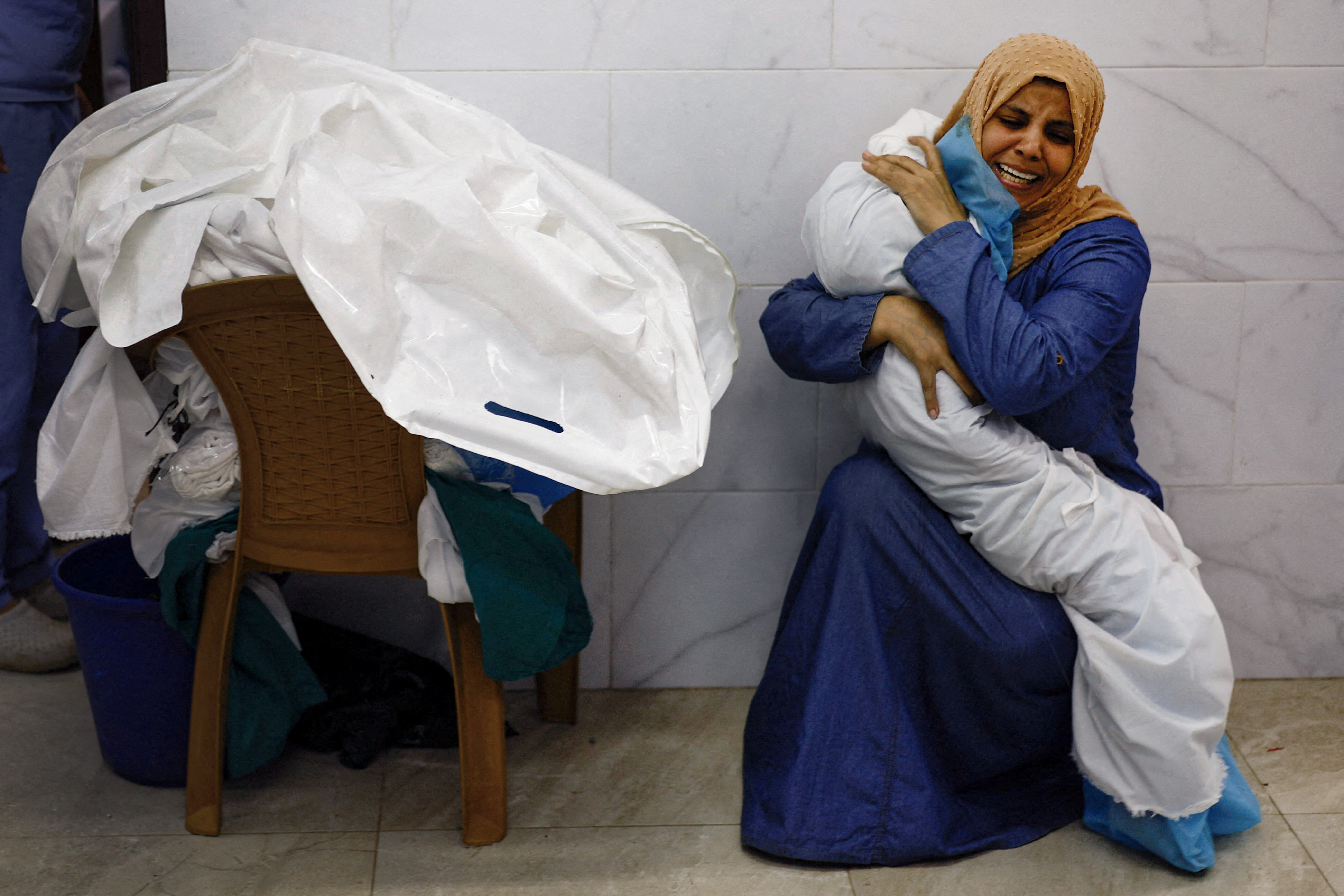 Palestinian woman Inas Abu Maamar, 36, embraces the body of her 5-year-old niece Saly, who was killed in an Israeli strike, at Nasser hospital in Khan Younis in the southern Gaza Strip, October 17, 2023. Reuters photographer Mohammad Salem was in Khan Younis on Oct. 17 at the Nasser Hospital morgue, where residents were going to search for missing relatives. He saw Inas squatting on the ground in the morgue, sobbing and tightly embracing Saly’s body. "I lost my conscience when I saw the girl, I took her in my arms," Inas said. "The doctor asked me to let go... but I told them to leave her with me." REUTERS/Mohammed Salem SEARCH "SALEM GAZA WOMAN" FOR THIS STORY. SEARCH "WIDER IMAGE" FOR ALL STORIES.