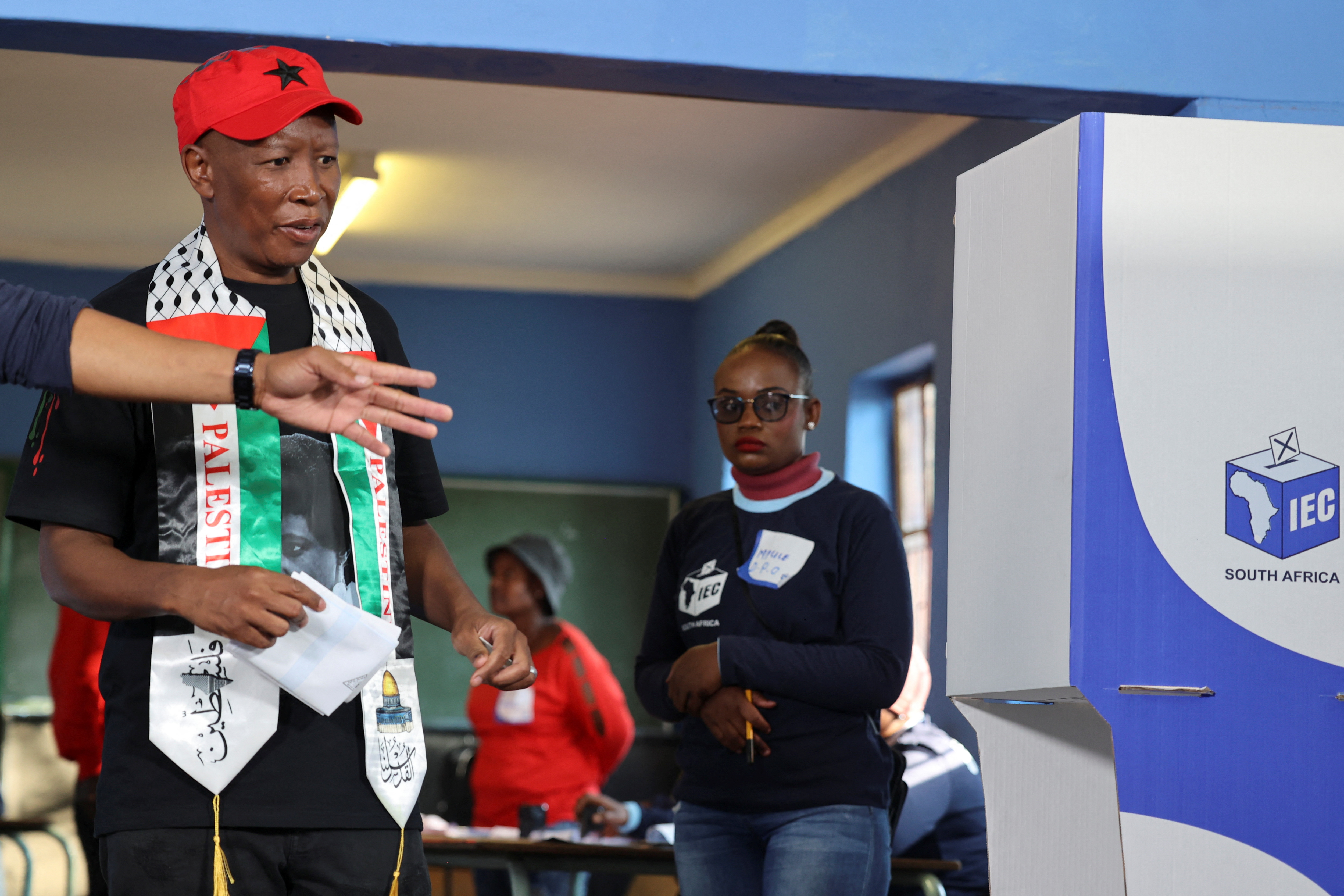 Julius Malema, wearing a Palestinian scarf, walks to a voting booth.