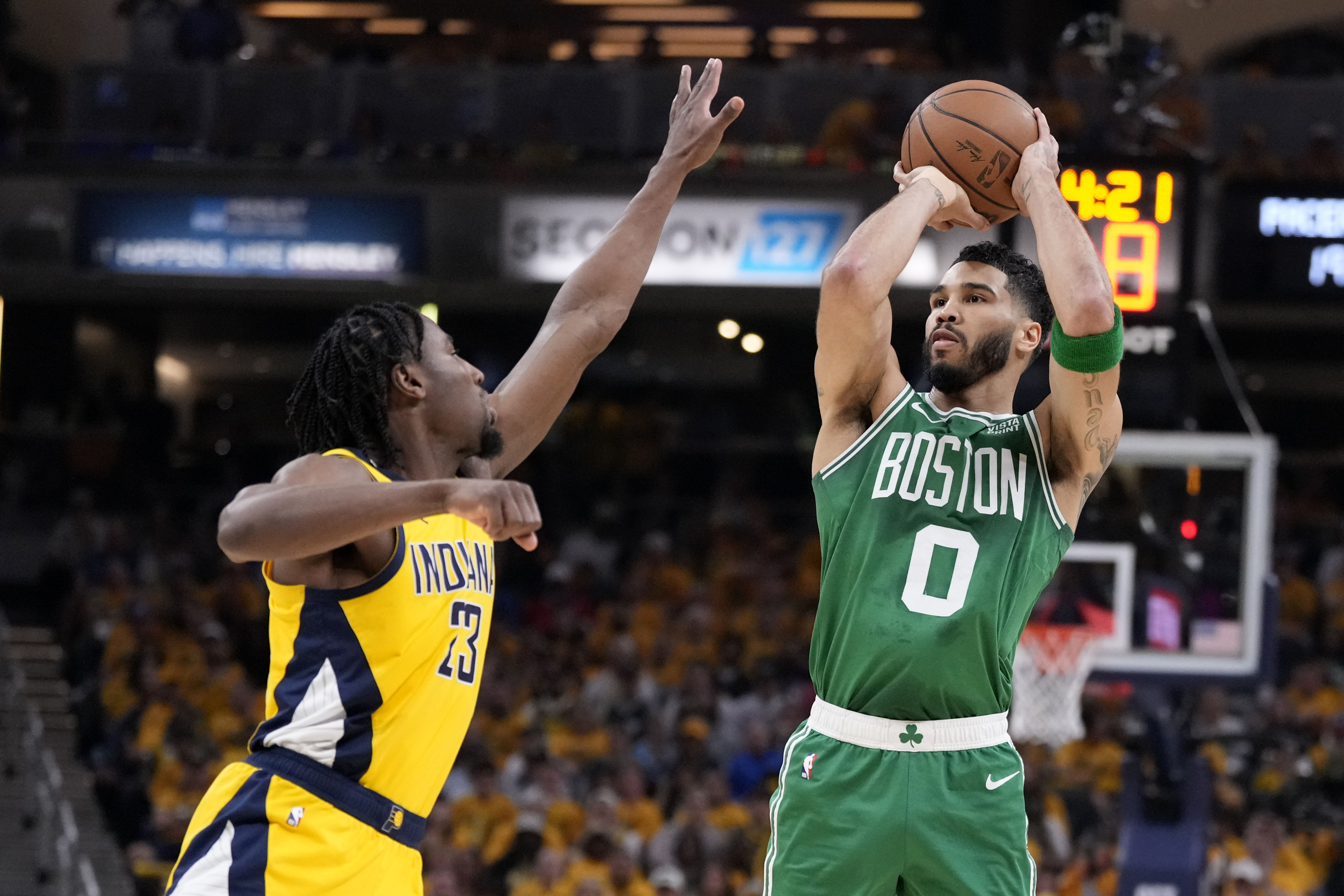 Basketball player shoots over defender.