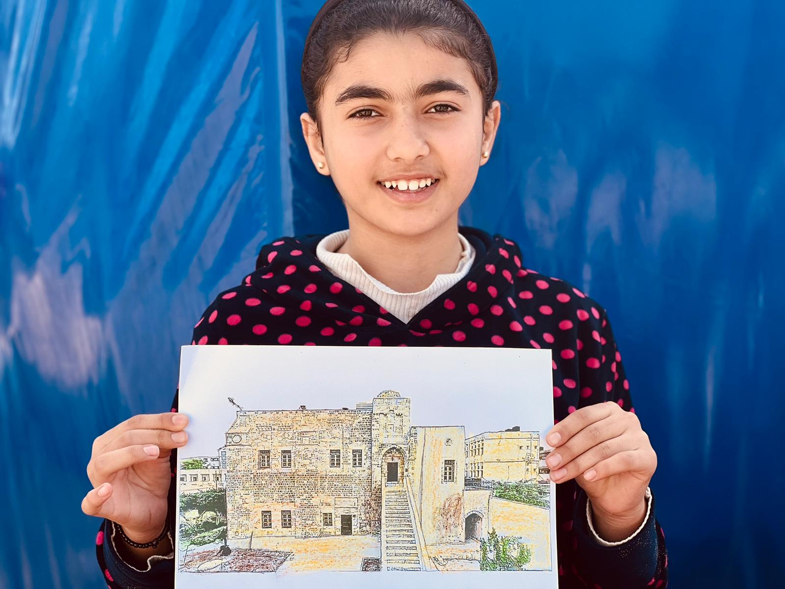 Thirteen-year-old Safa’a (not her real name) proudly poses with her picture of Qasr Al-Basha, Gaza City, at one of the classes run by Palestinian organisation Culture and Free Thought Association (CFTA).