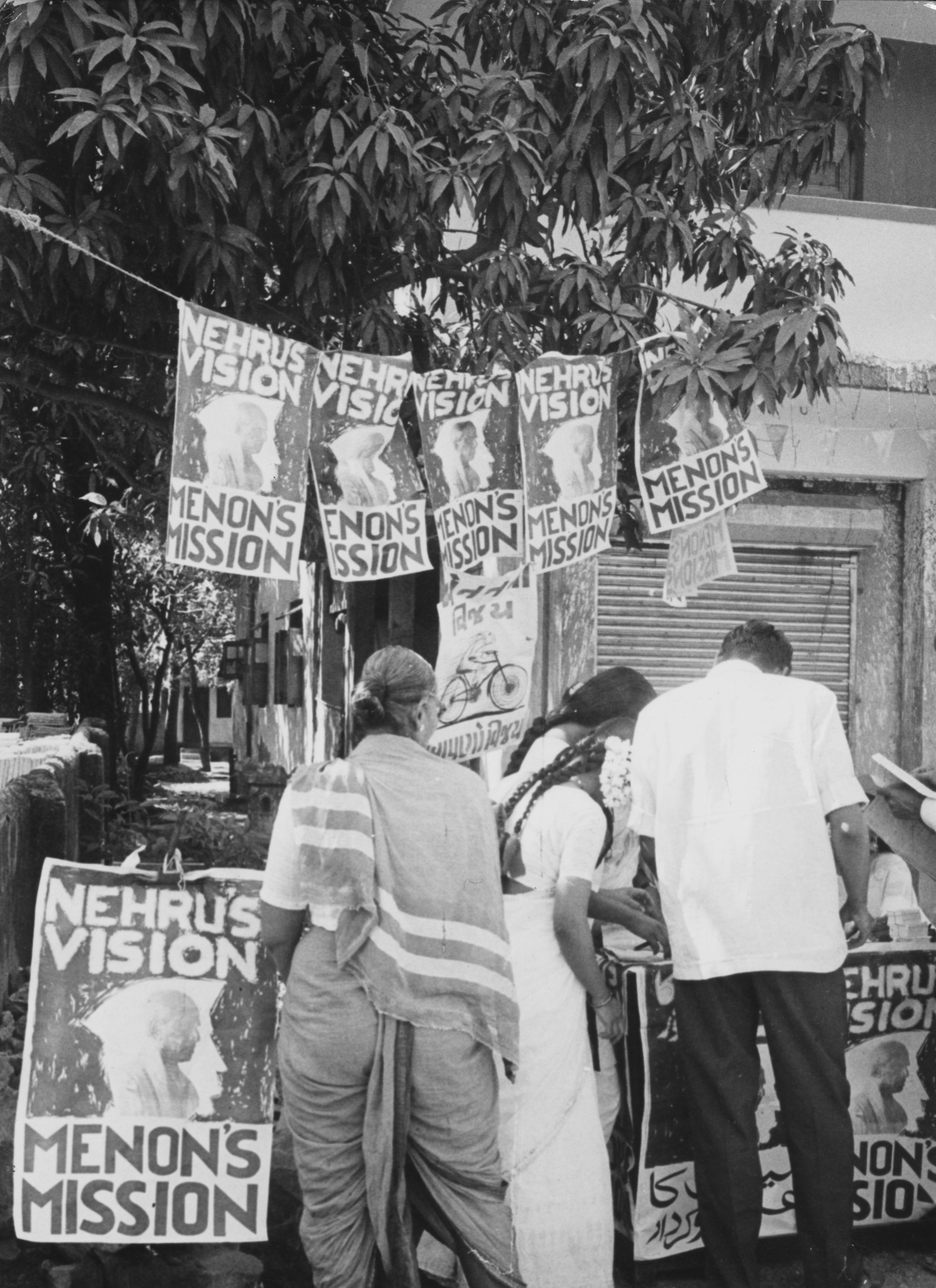 People in Bombay voting in the national election, beside posters advertising the political visions of Indian statesmen Pandit Nehru and Krishna Menon