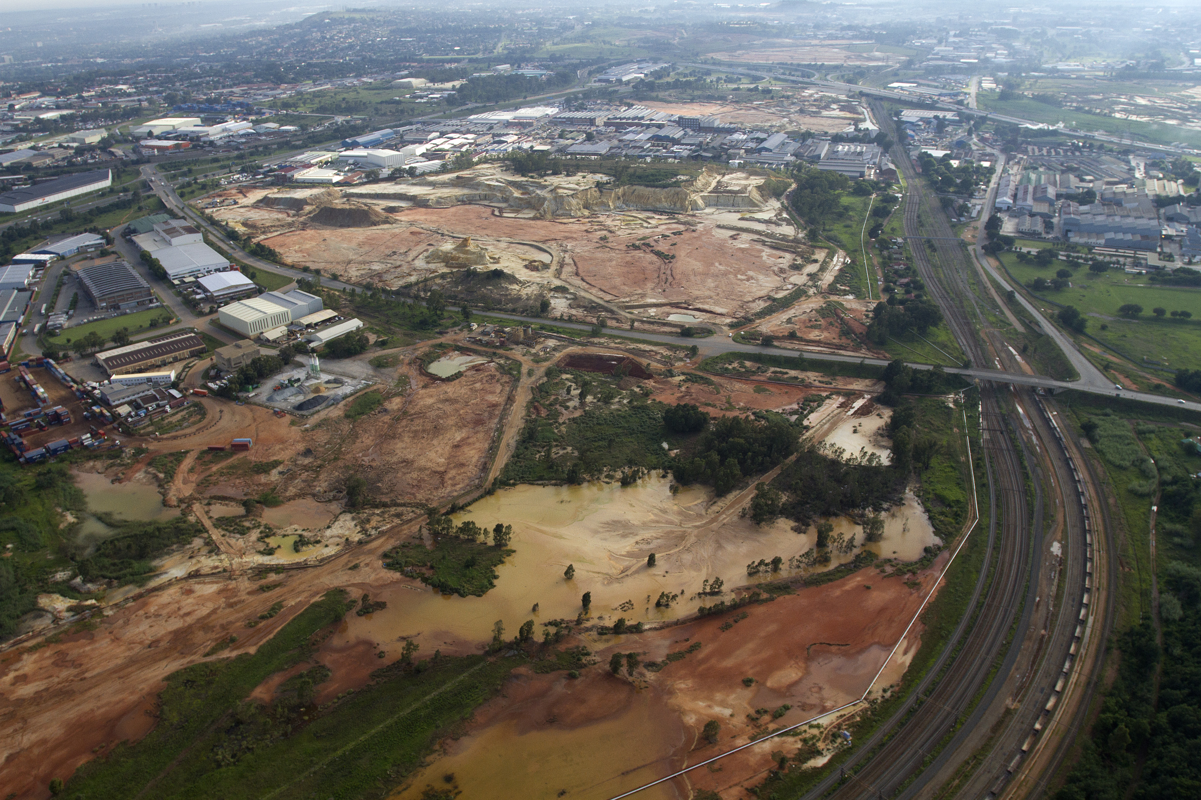 A traffic highway and railway lines, right, pass waste ground and a mine dump in this aerial view of Johannesburg, South Africa, on Saturday, Dec. 14, 2013. While Johannesburg flourished after the discovery of gold in 1886 the stress that the mining has placed on underground rock formations has increased seismic activity. Photographer: Dean Hutton/Bloomberg via Getty Images
