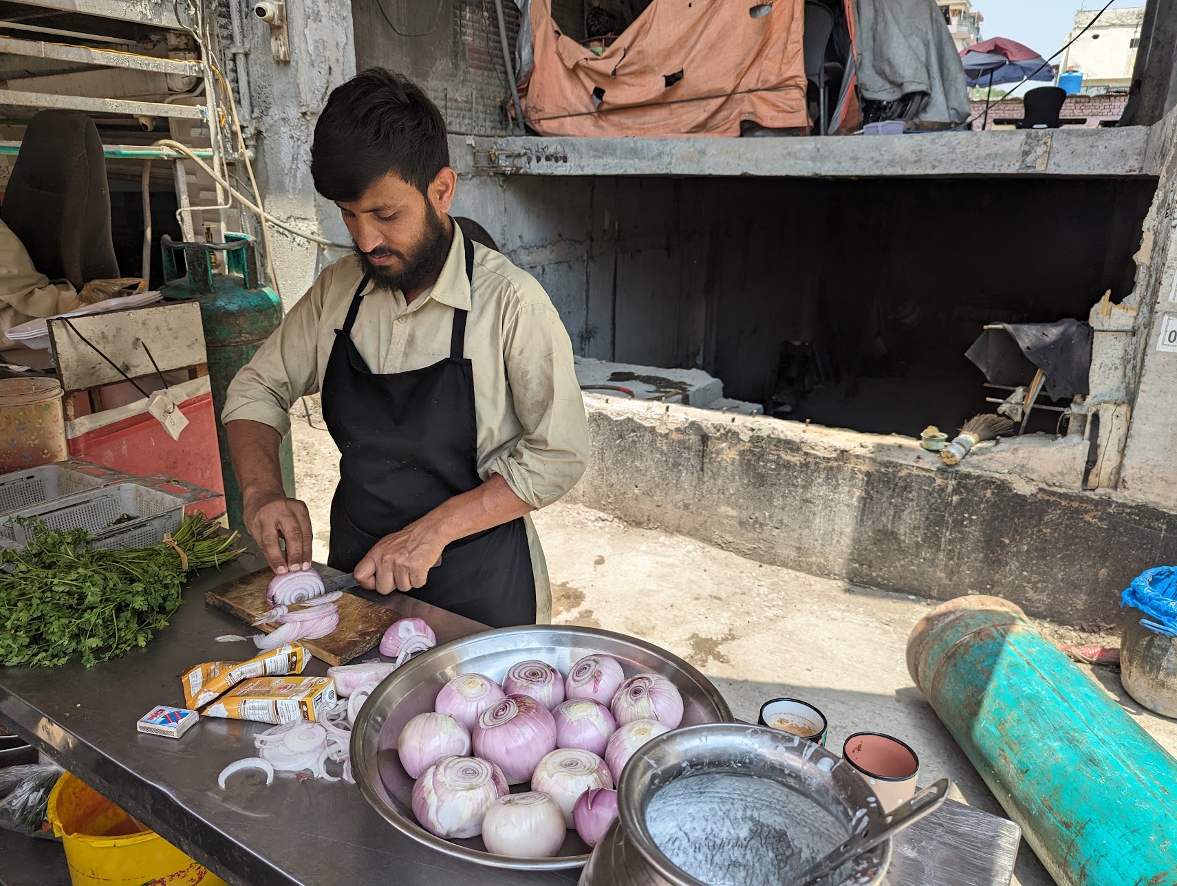Chef Hamid Baloch slices onions at his cafe in Islamabad. [Abid Hussain/Al Jazeera]