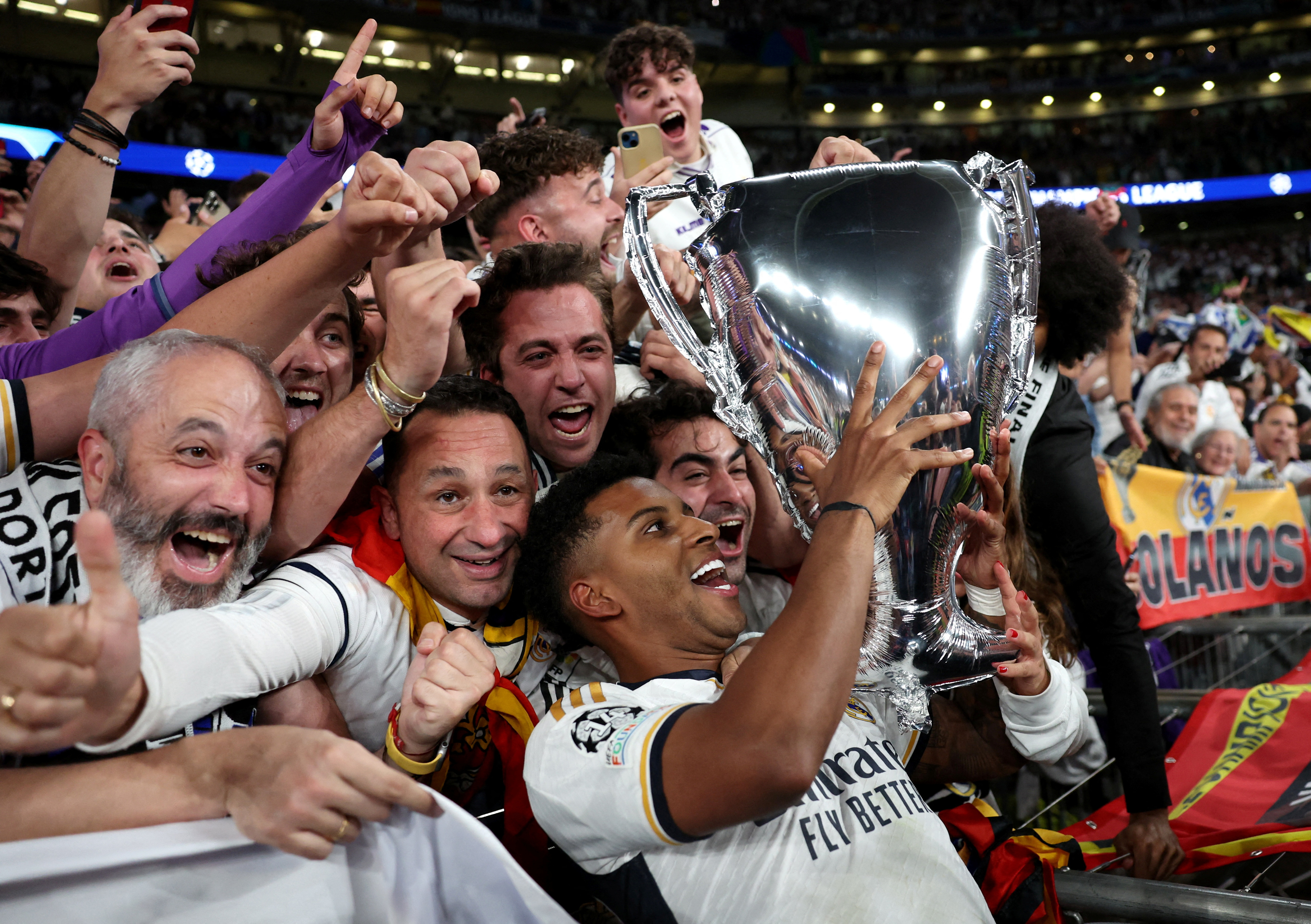 Real Madrid's Rodrygo celebrates with a balloon trophy and the fans after winning the Champions League final