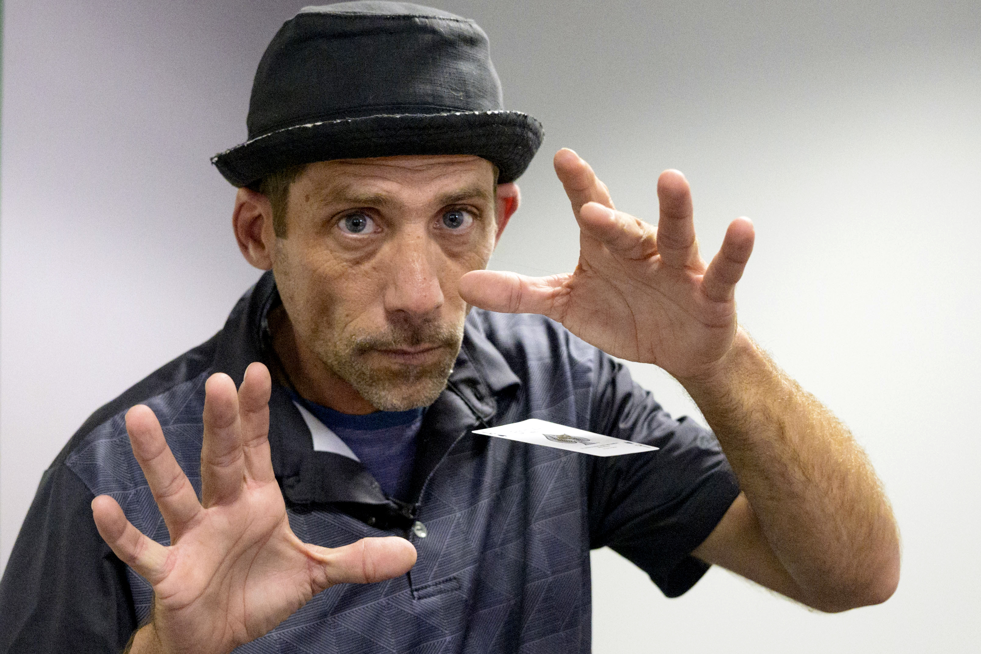 Paul Carpenter, a magician, appears to float a playing card between his two outstretched hands.