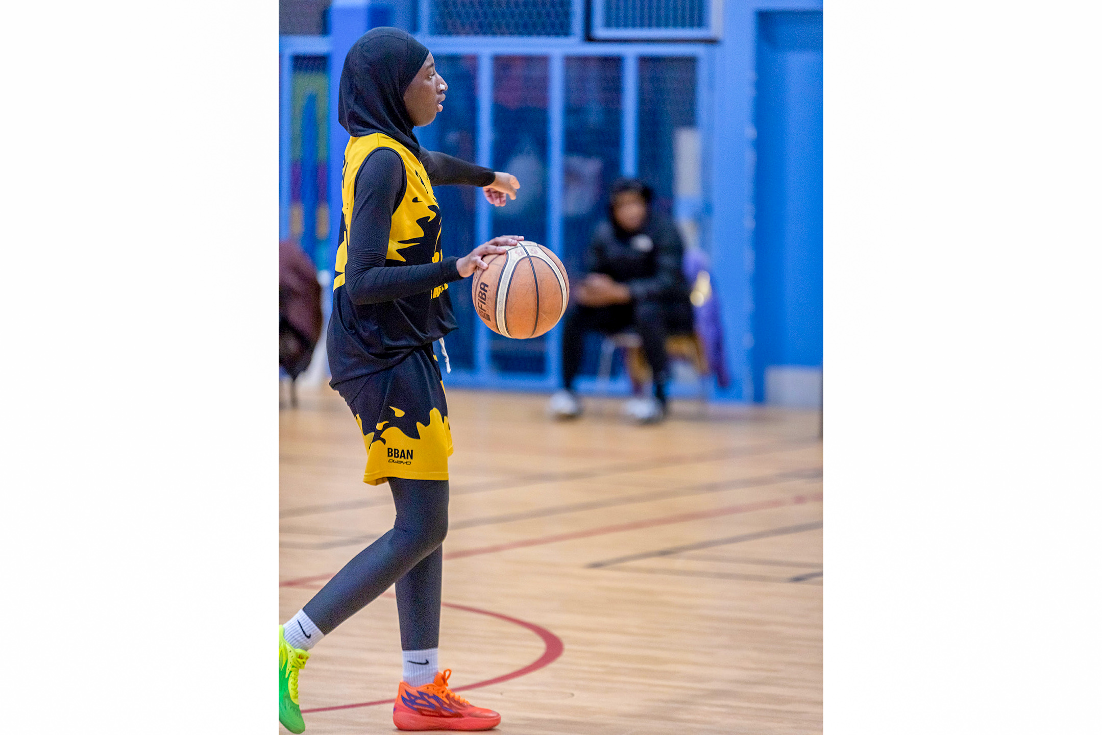 Female dribbling basketball on court.