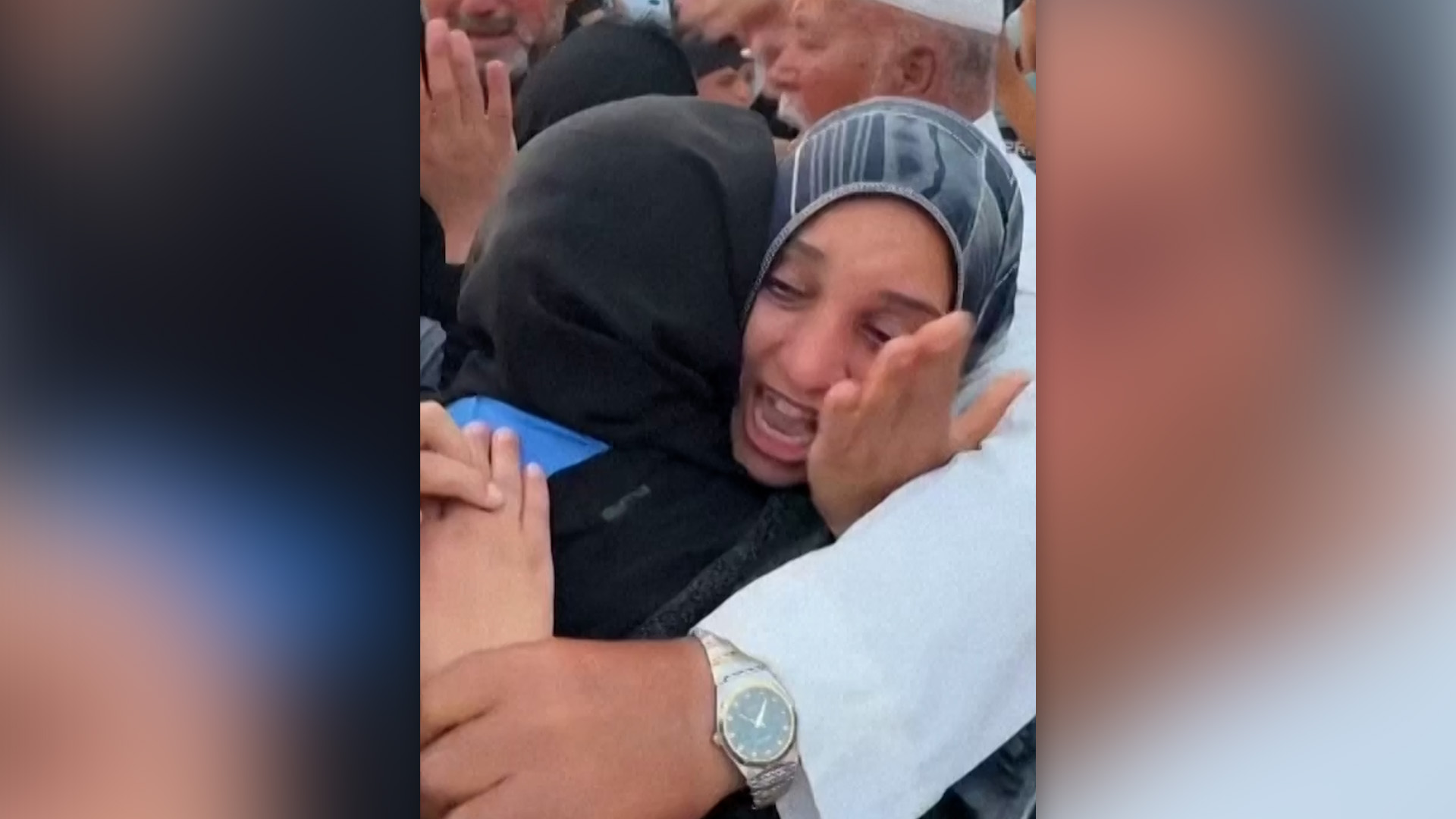 A woman grieves while others hug her.
