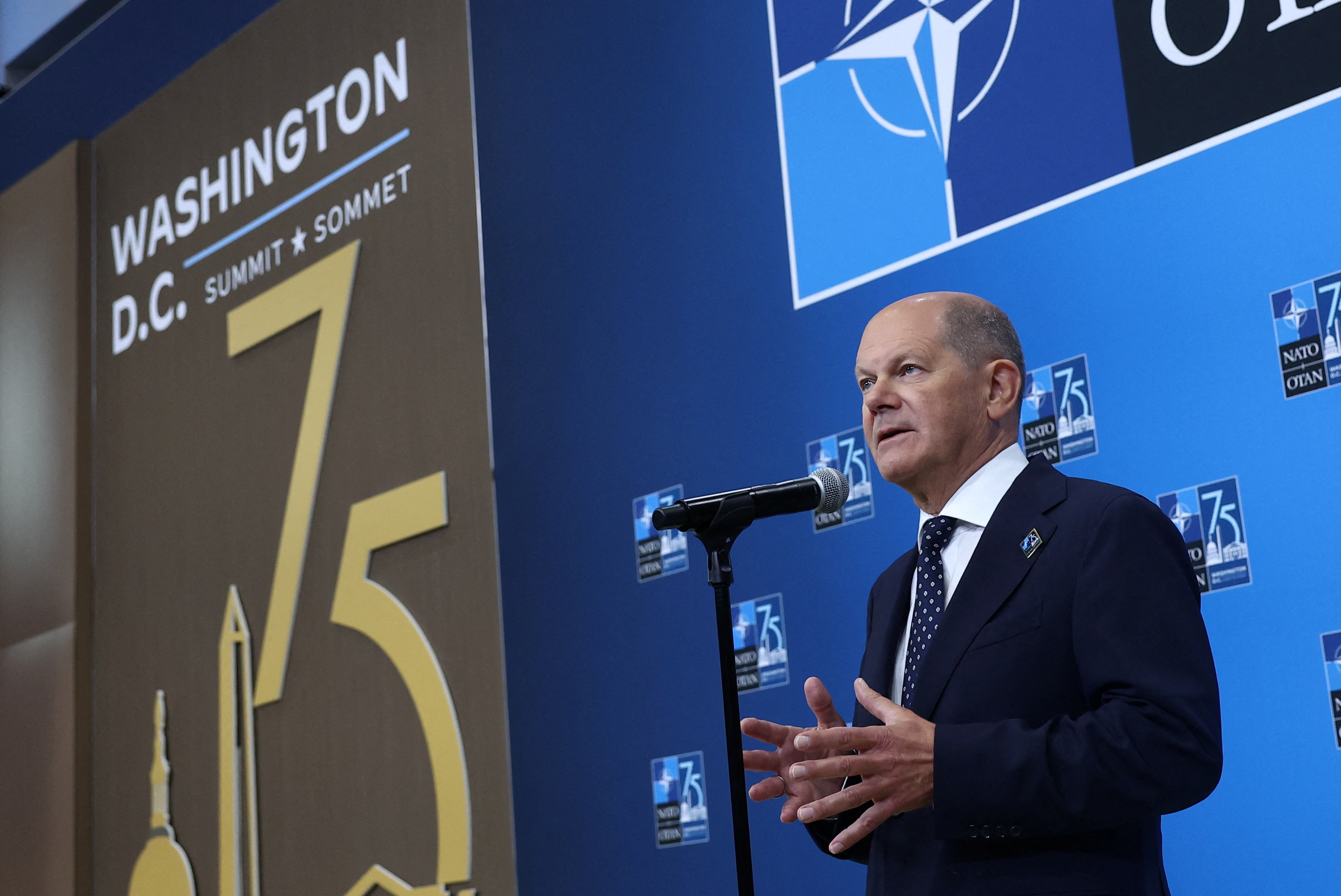 German Chancellor Olaf Scholz speaks at a microphone during the NATO summit