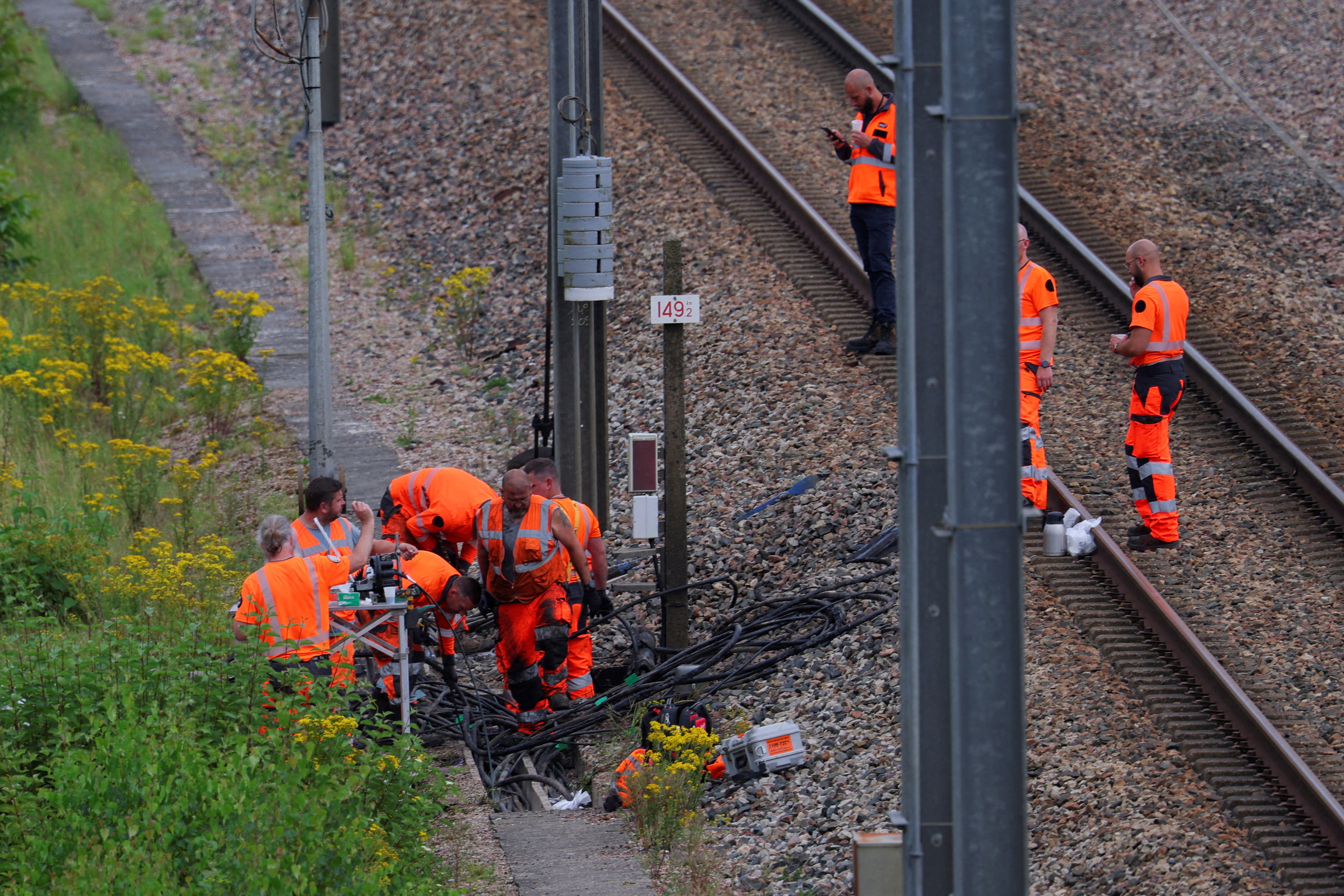 Railway workers and law enforcement officers work at a site where vandals targeted France's high-speed train network