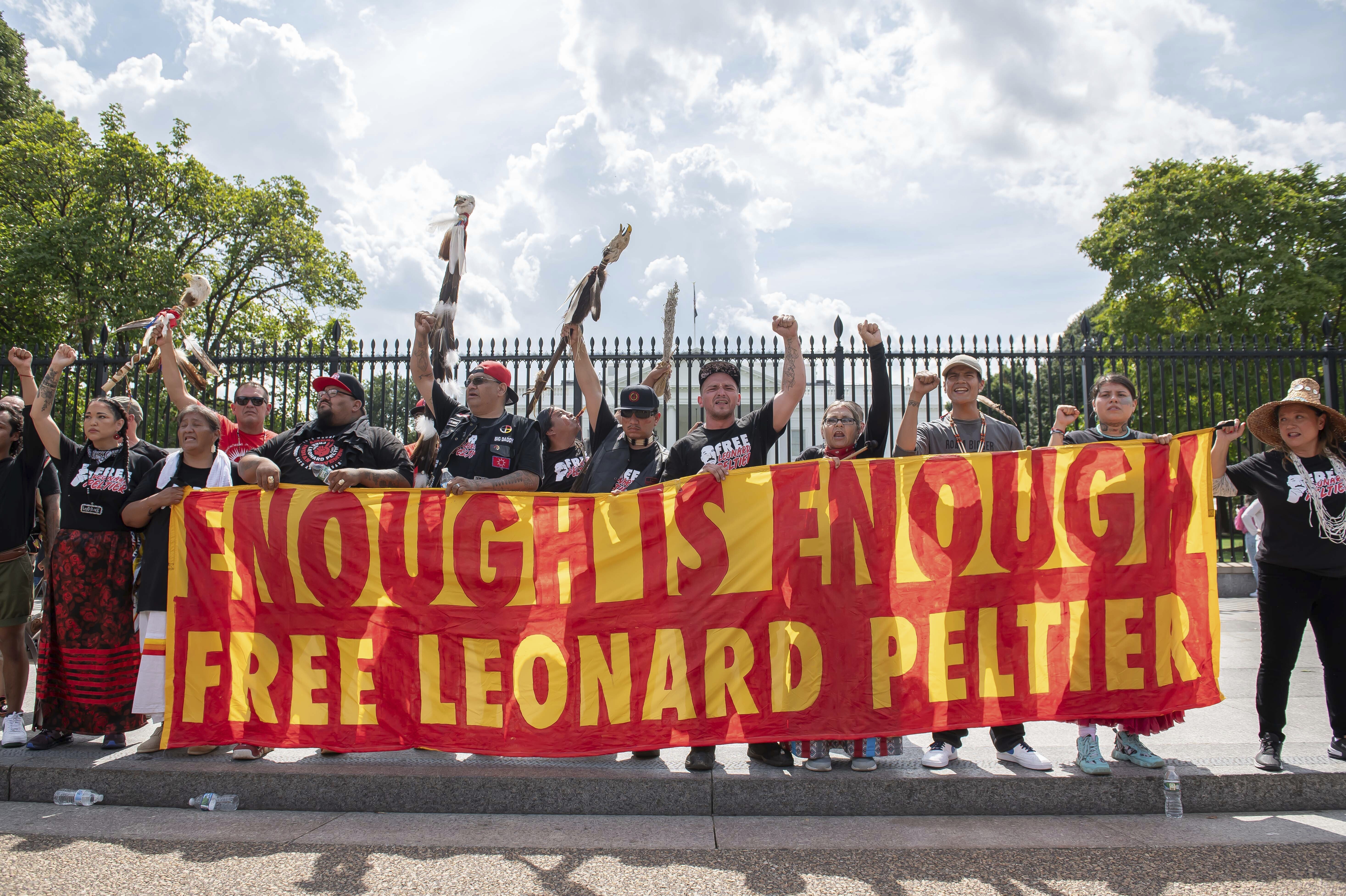 Protesters hold up a banner sign that reads: "Enough is enough! Free Leonard Peltier."