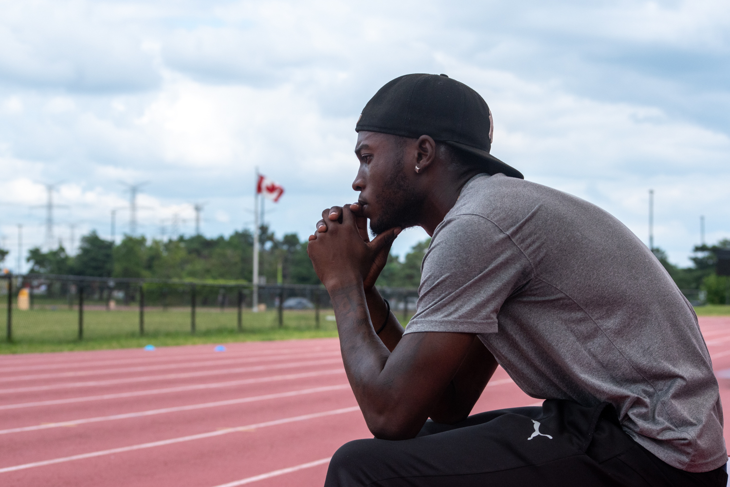 Tamarri Lindo sits on a bench, looking out over an outdoor track.
