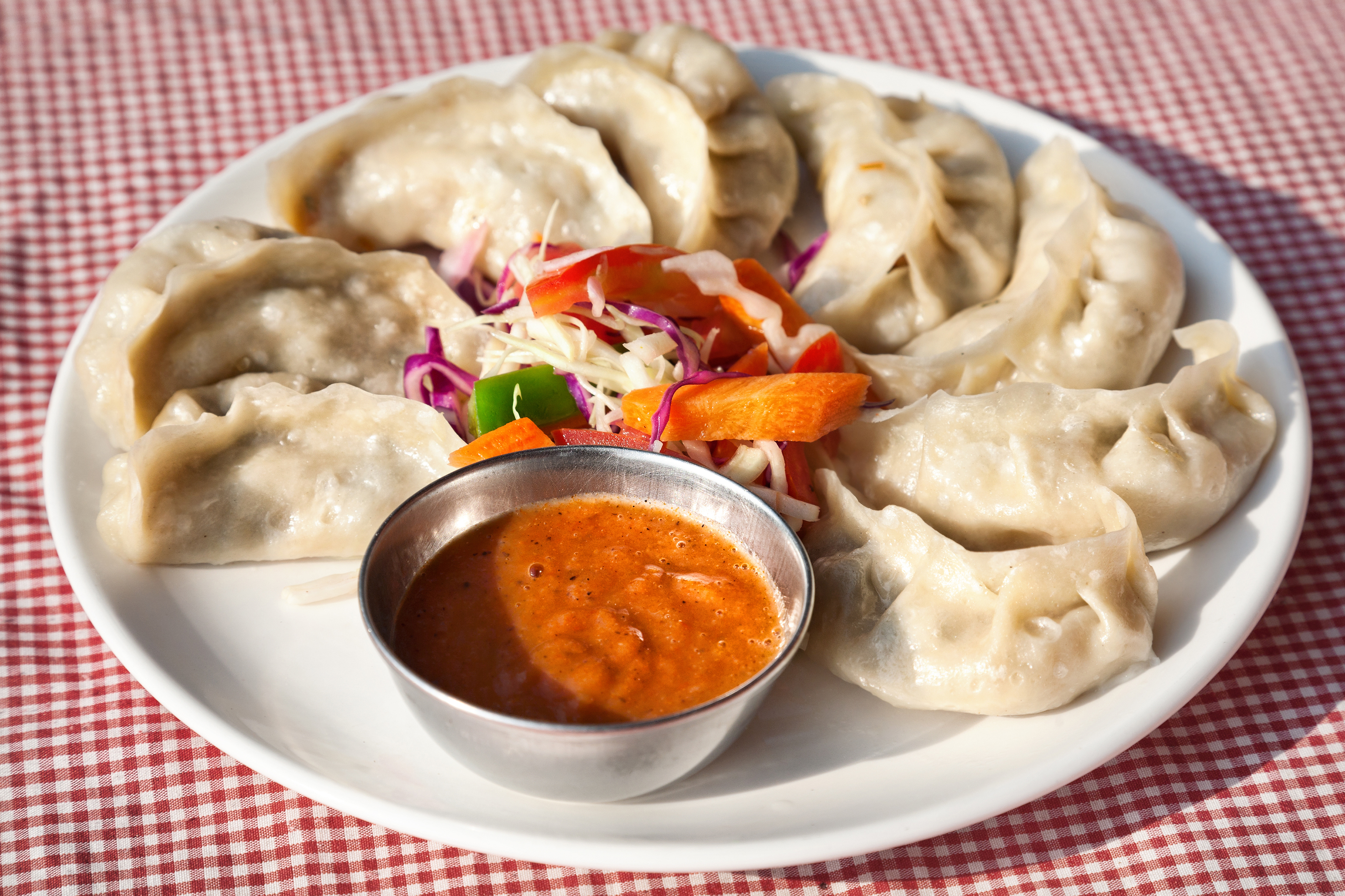 A plate of traditional Nepalese dumplings (momos) served with tomato chutney and fresh salad [Getty]