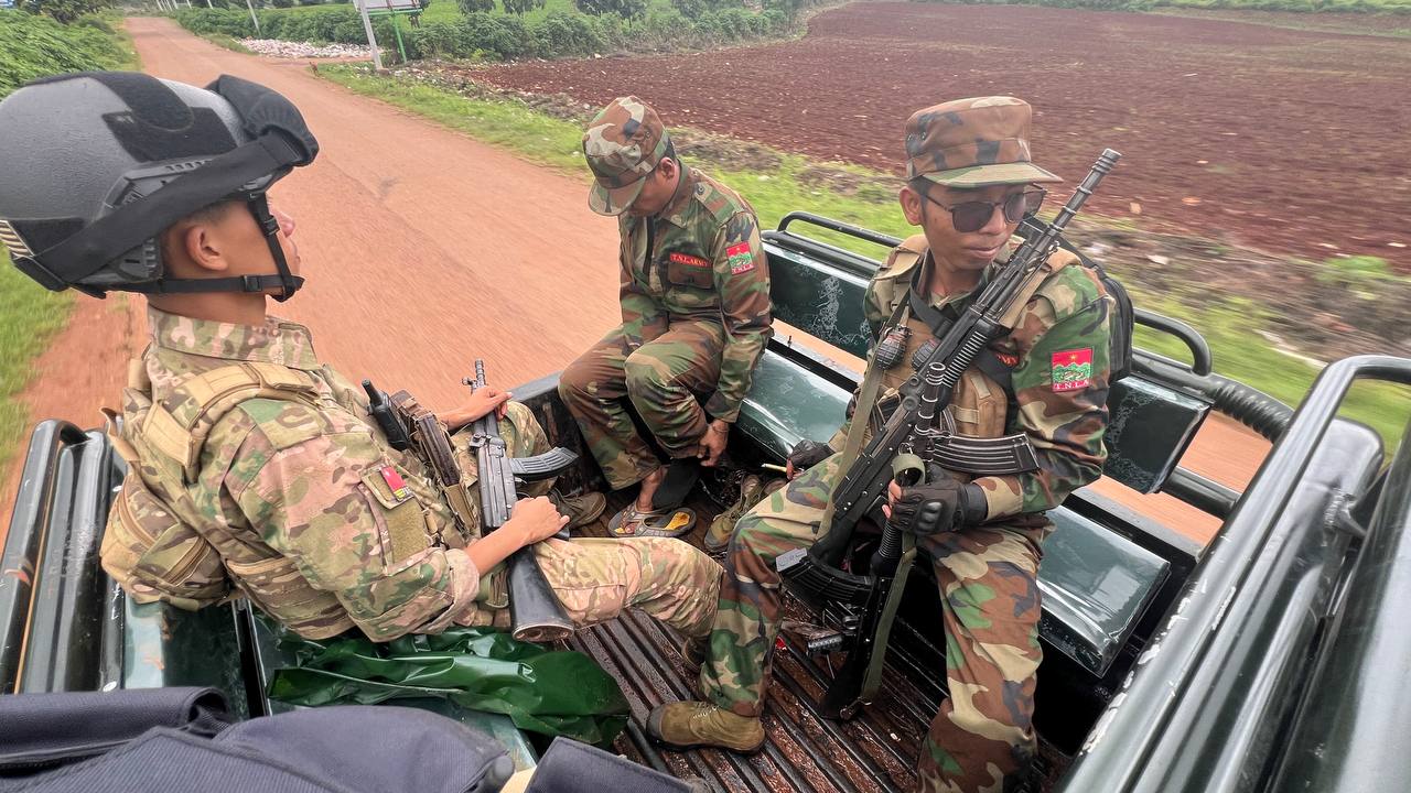 Anti-coup fighters on the back of a pick-up truck. They are in uniform and holding their weapons.