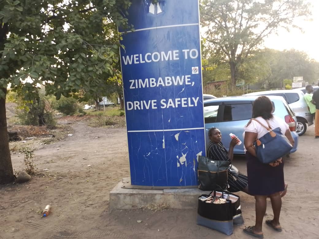 People leaving Zambia gather at the border crossing into Zimbabwe