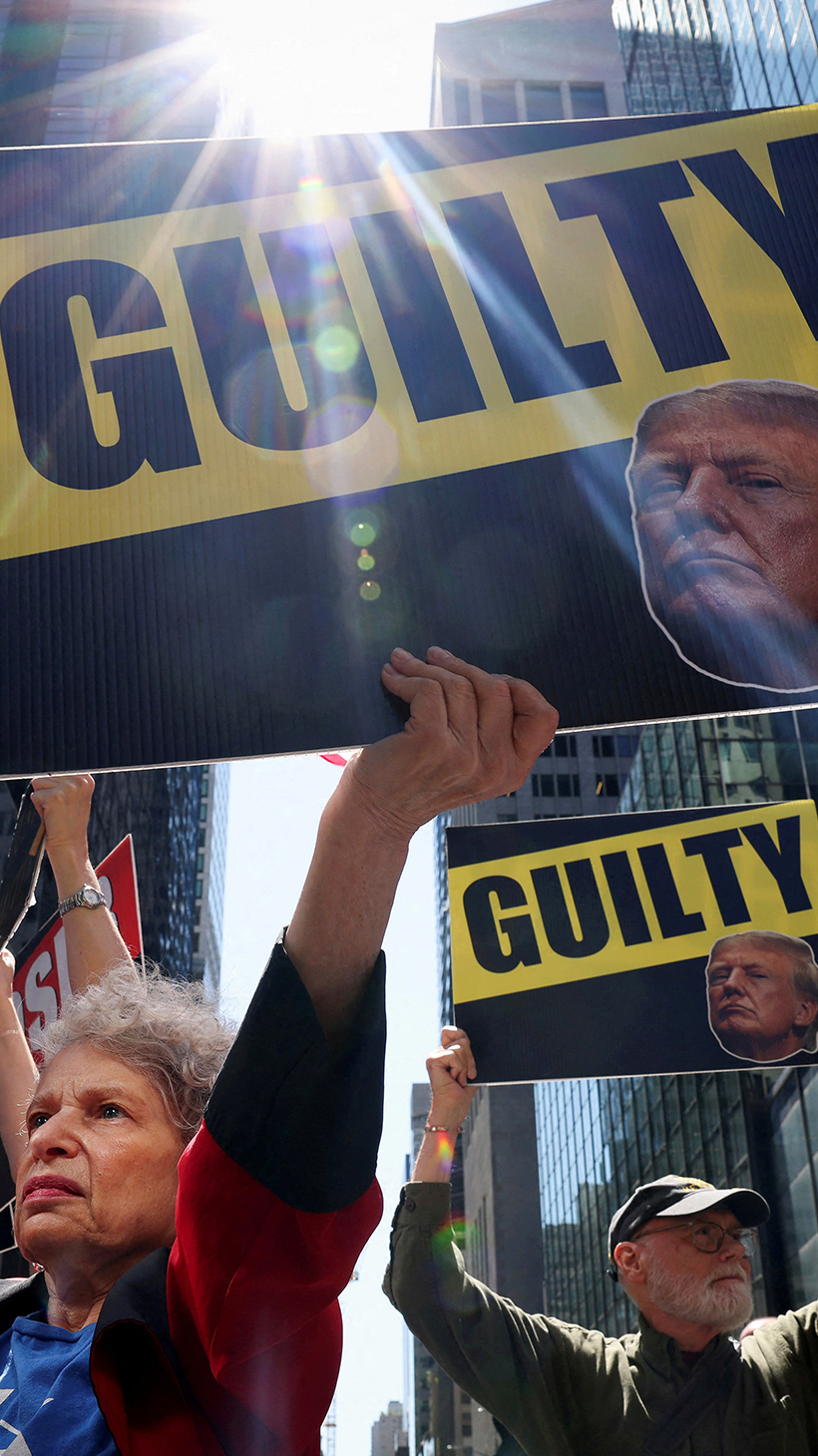 A protester in New York lifts up signs with Donald Trump's face with the word "Guilty"