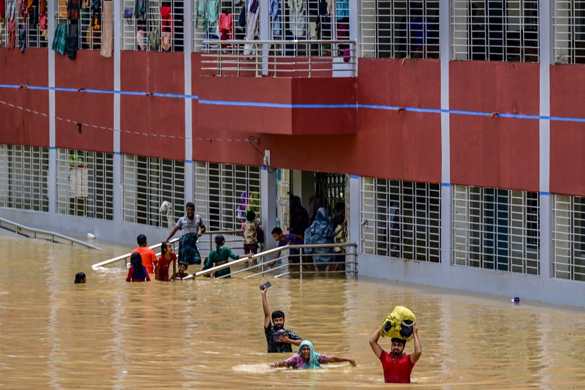 People wade through flood waters near a temporary shelter