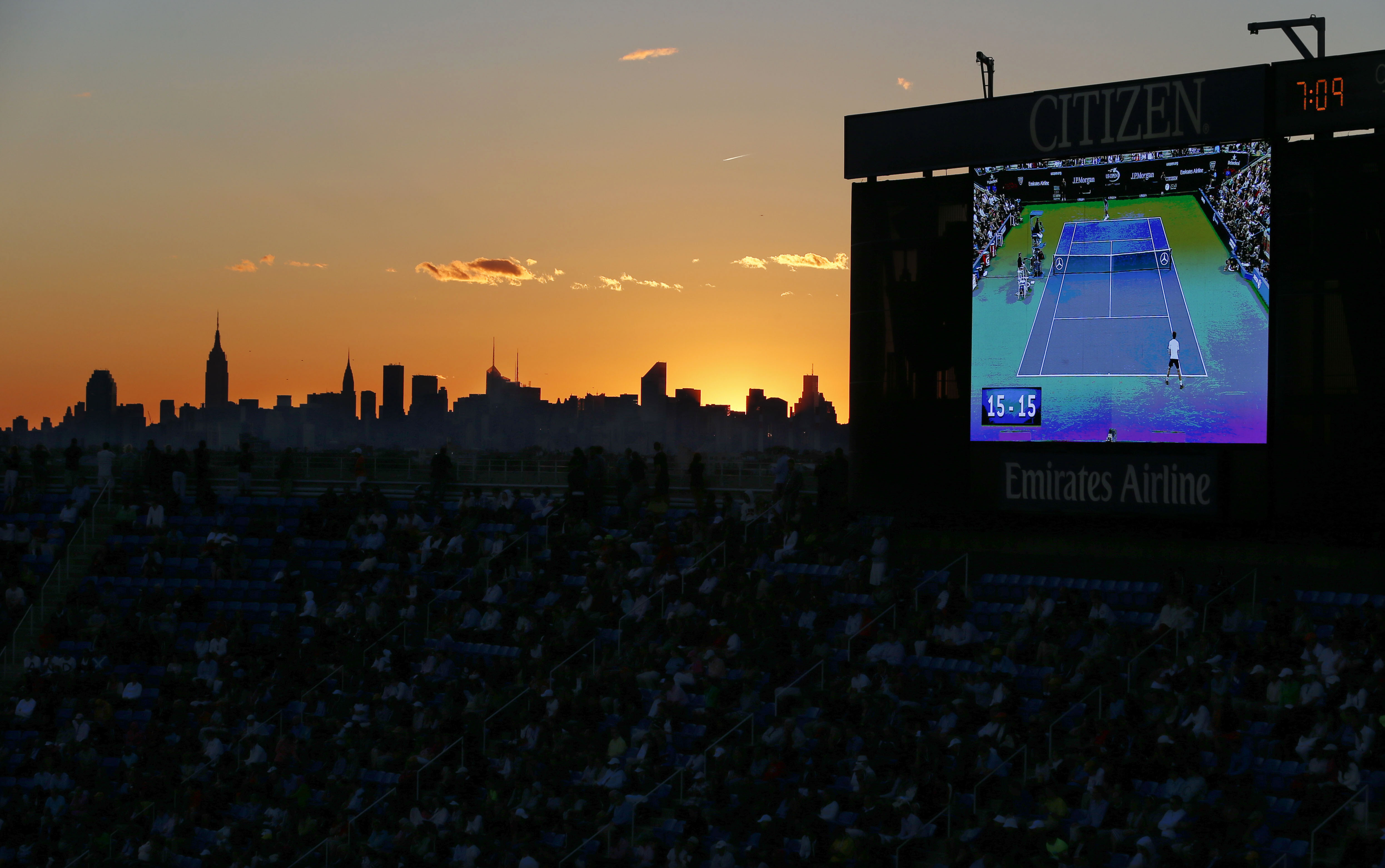 FILE - The championship match between Britain's Andy Murray and Serbia's Novak Djokovic is shown on a big screen as the sun sets behind the New York City skyline at the 2012 U.S. Open tennis tournament, Monday, Sept. 10, 2012, in New York. The 2024 U.S. Open begins Monday, Aug. 26.(AP Photo/Julio Cortez, File)