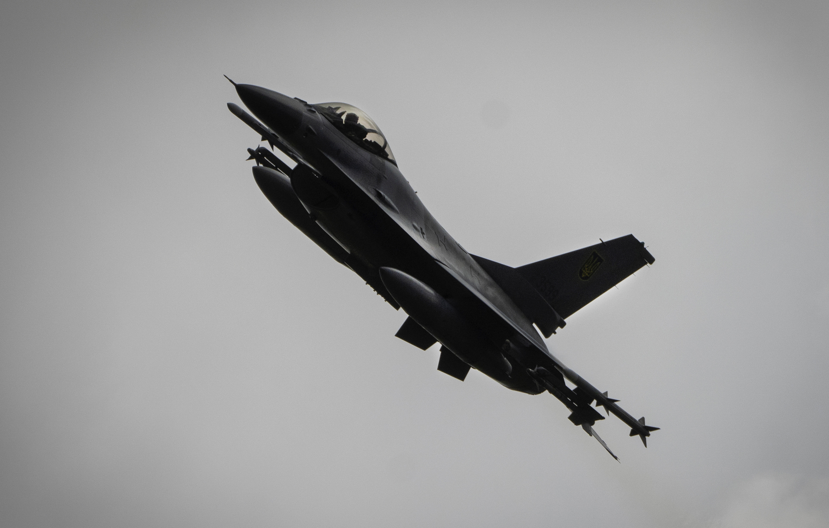 An F-16 fighter jet with the Ukrainian air force. It is flying from right to left