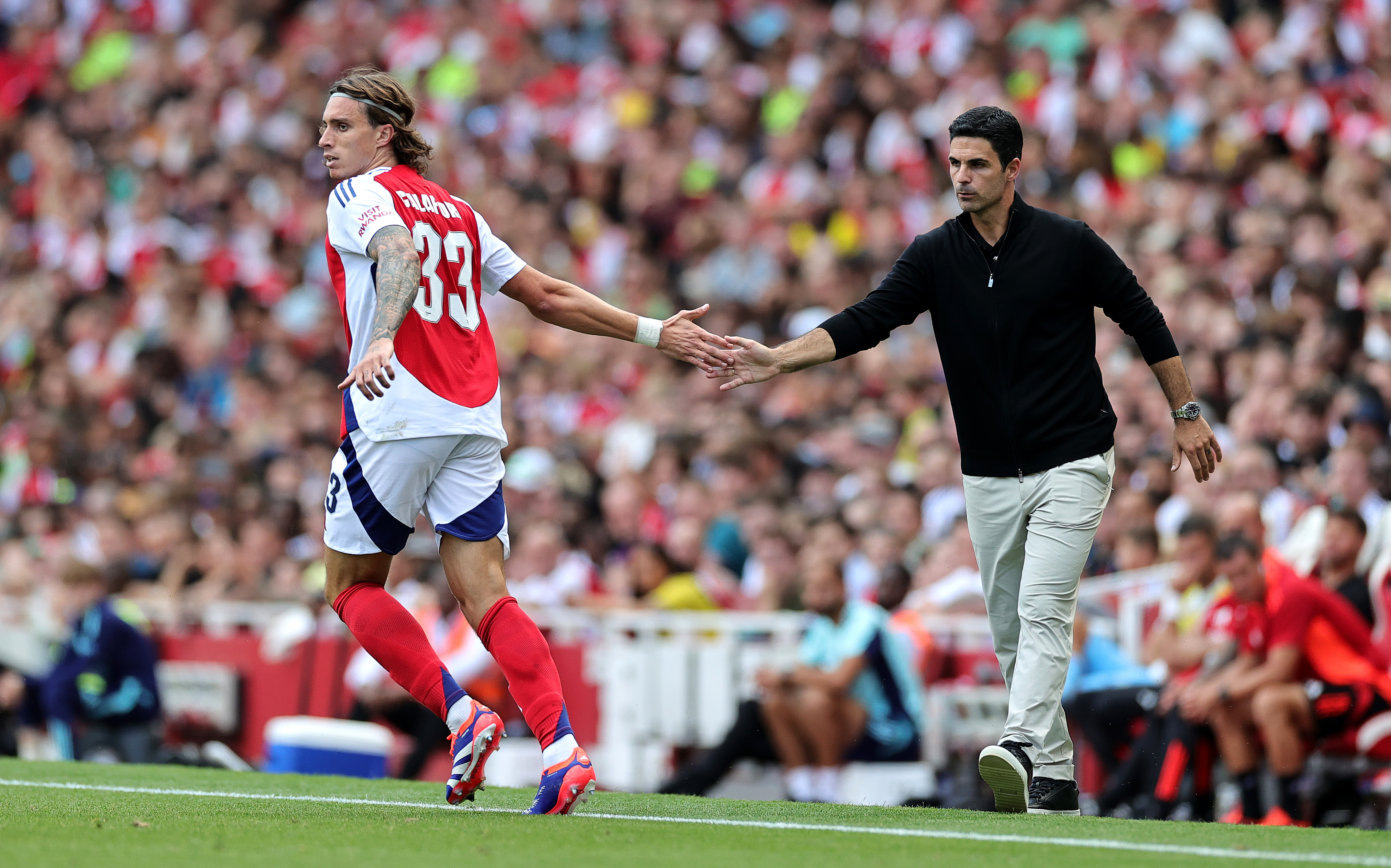 LONDON, ENGLAND - AUGUST 11: Riccardo Calafiori of Arsenal touches hands with Arsenal manager Mikel Arteta during the pre-season friendly match between Arsenal and Olympique Lyonnais at the Emirates Stadium on August 11, 2024 in London, England. (Photo by David Rogers/Getty Images)