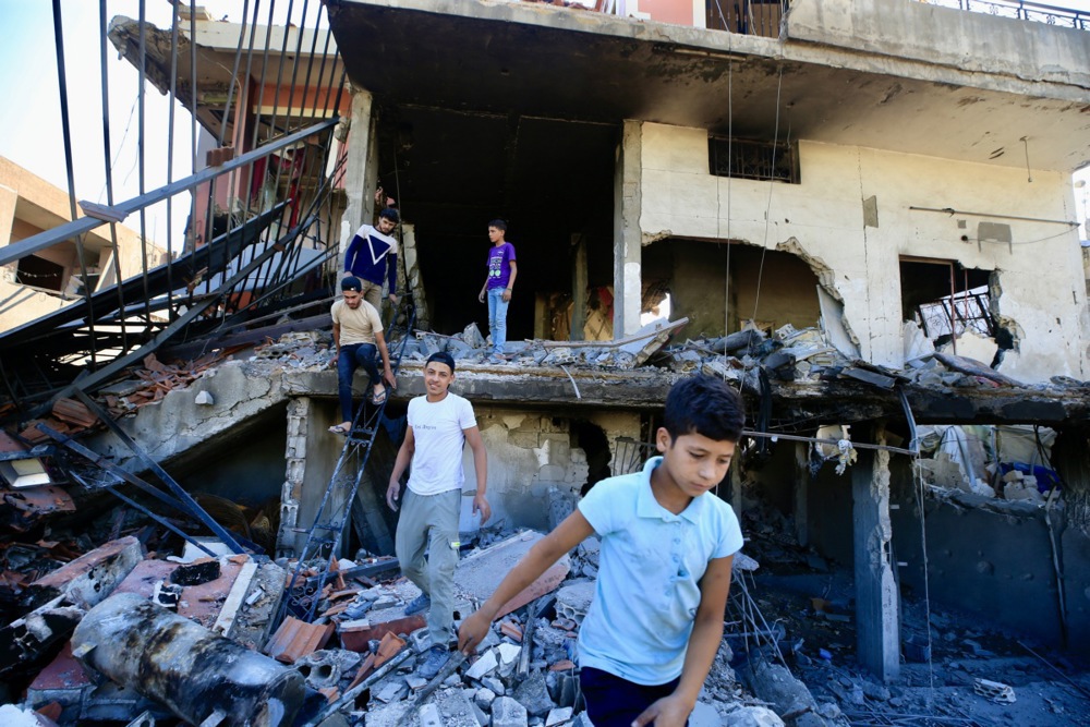 children walk away from a bombed building