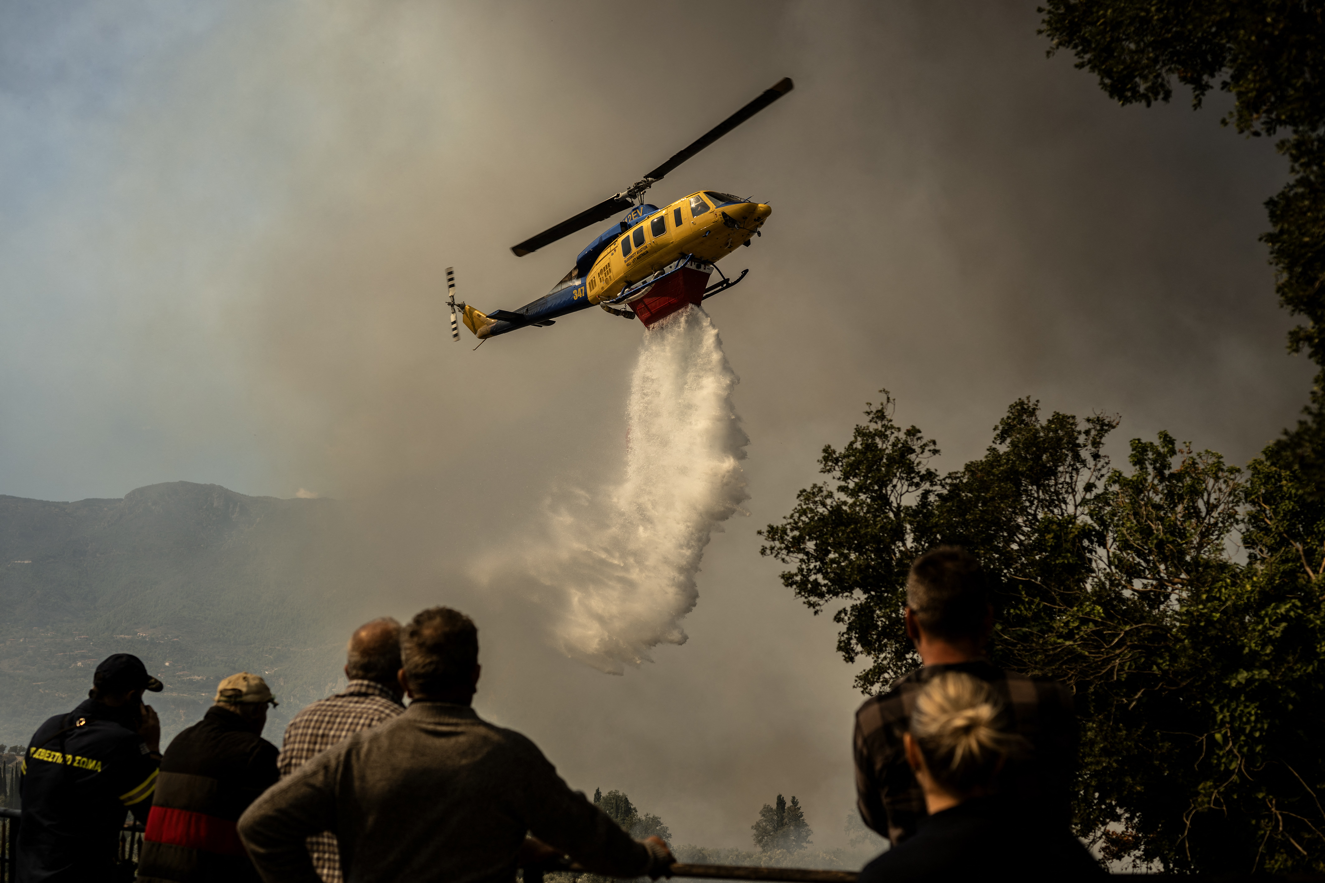 A firefighting helicopter drops water drop as a wildfire burns in the village of Pyrgos, near Corinth, on September 30