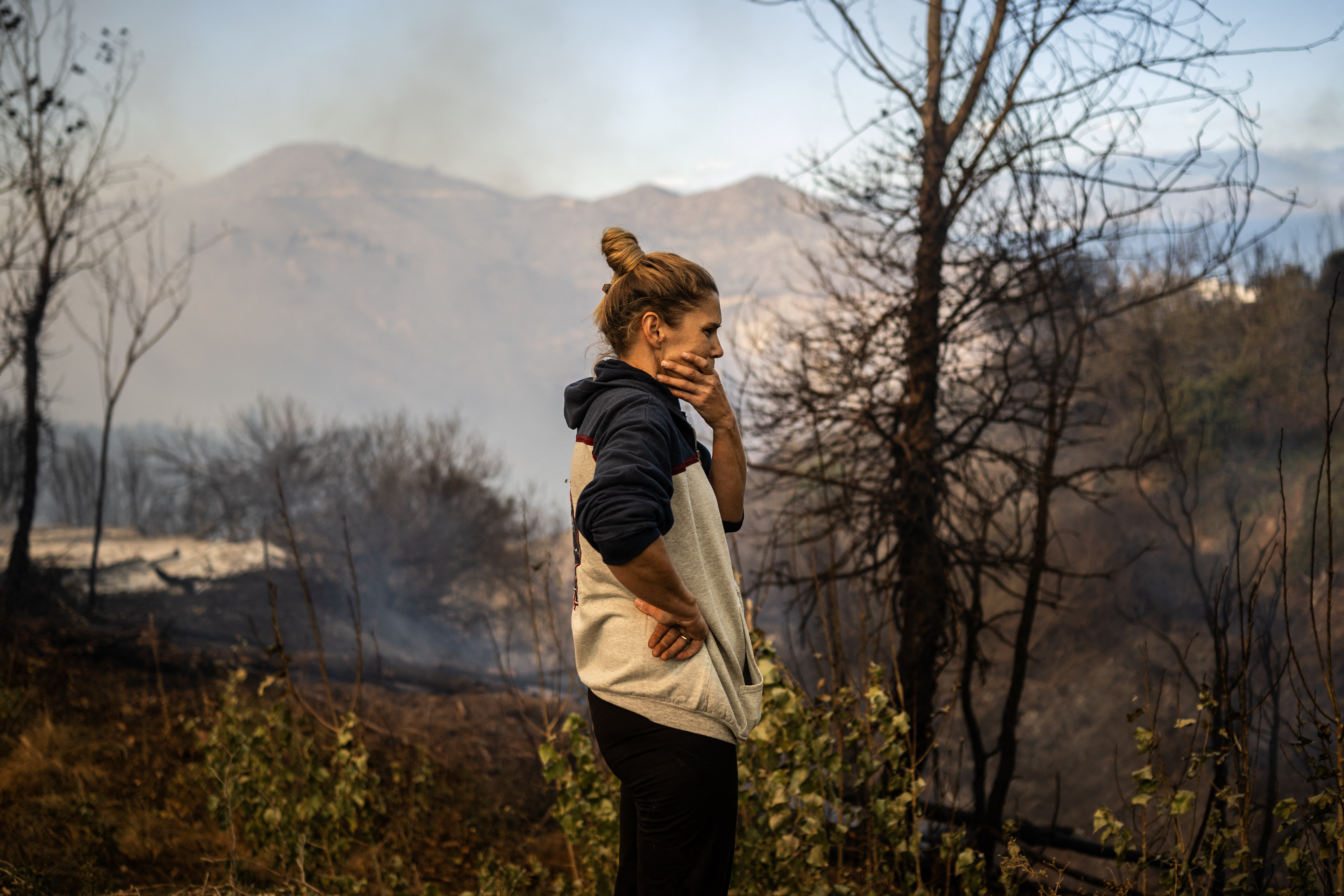 A local resident reacts as a wildfire burns in the village of Pyrgos, near Corinth, on September 30