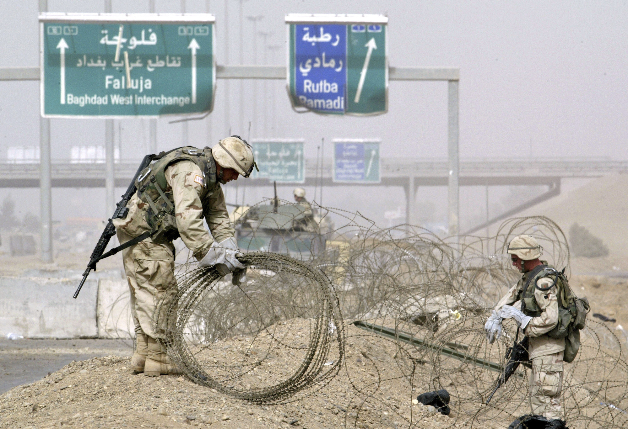 US troops clear rolls of razor wire from the main entrance to Fallujah, Iraq, April 30, 2004