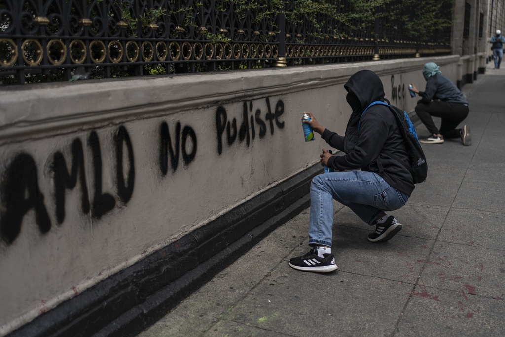 Students paint the words ‘AMLO you could not’ during a protest before the 10th anniversary of the disappearance of 43 teaching college students, in Mexico City on September 23