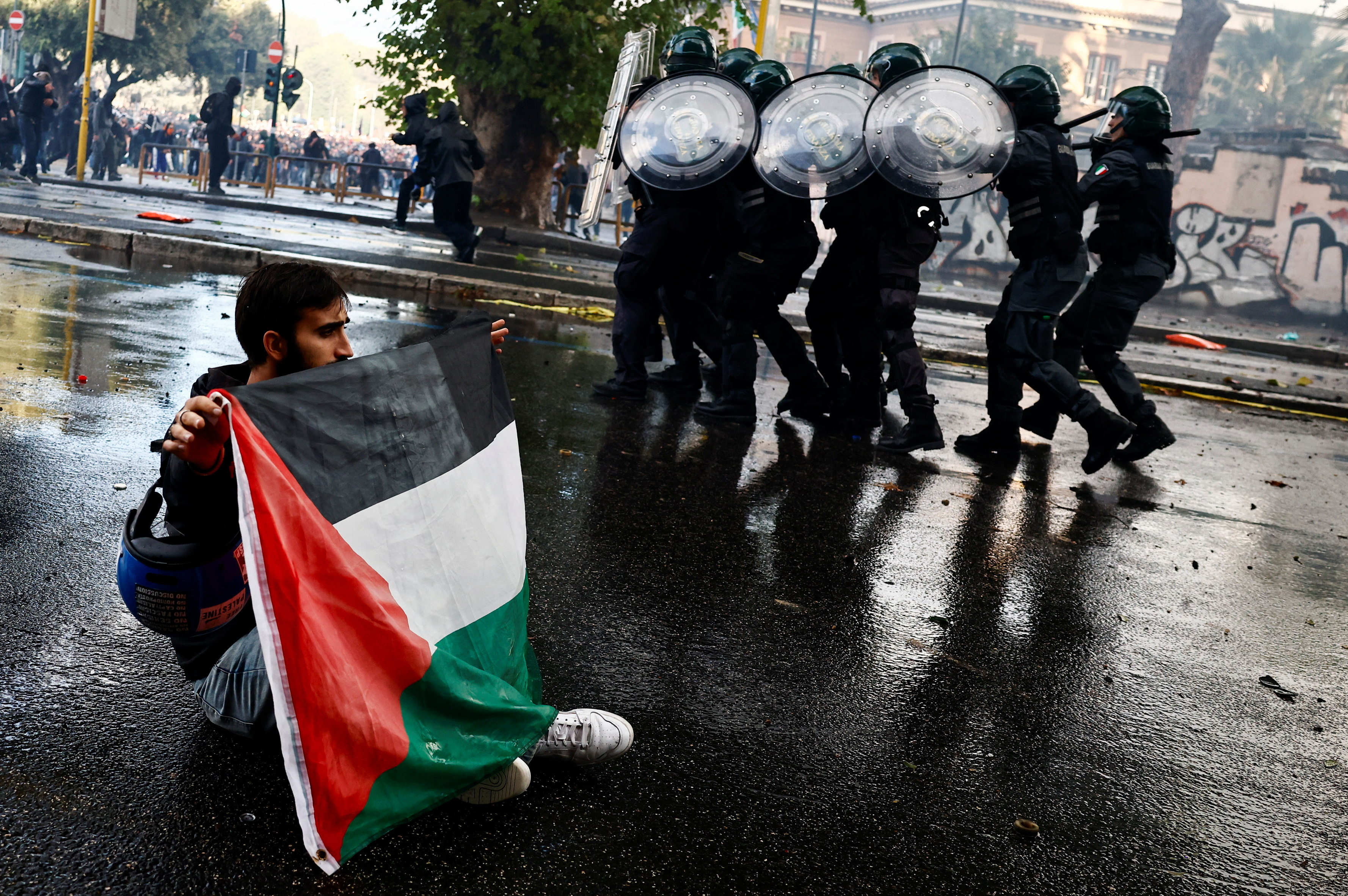 A protester holds a Palestinian flag near members of Carabinieri at a protest