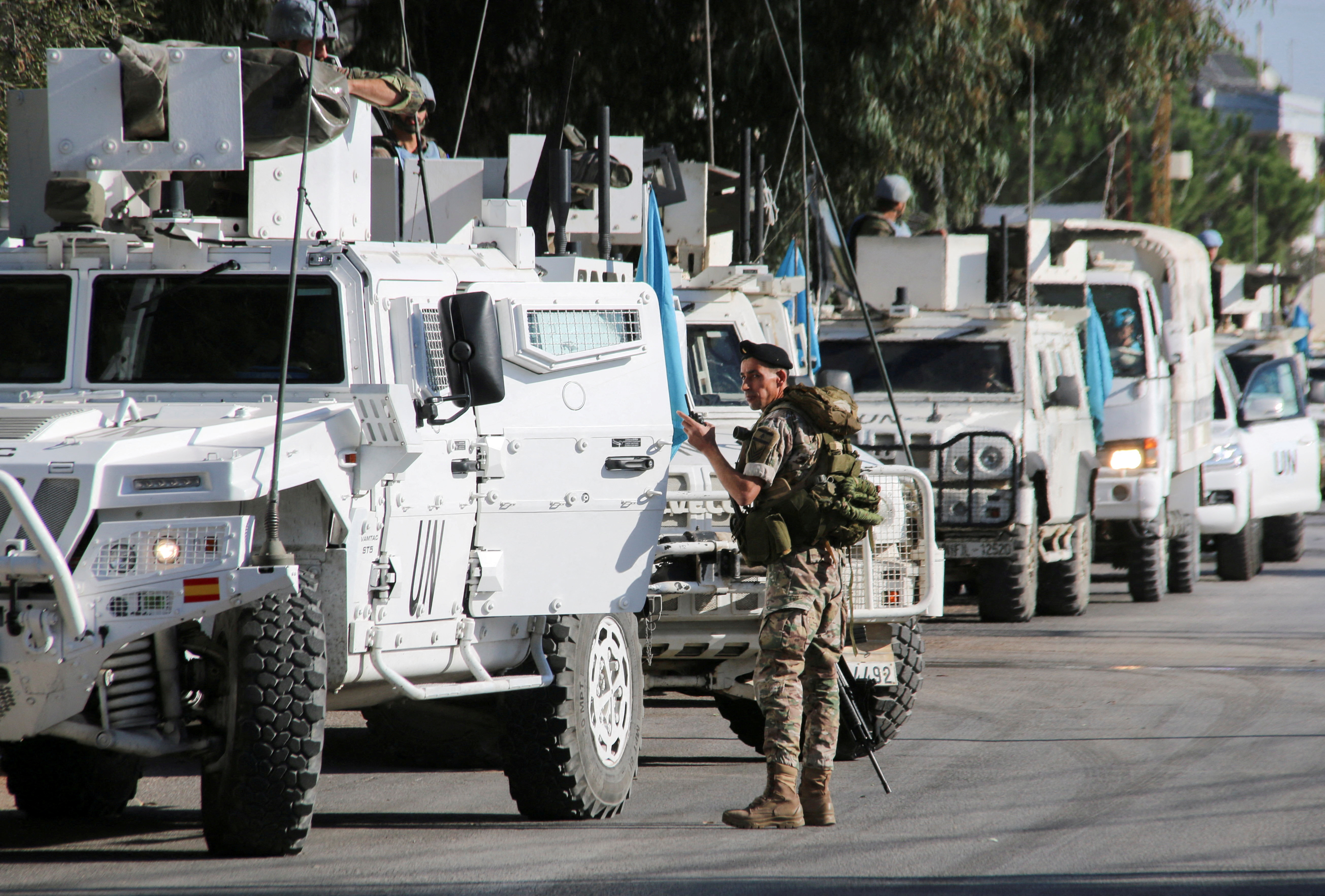 A Lebanese army soldier stands near UN peacekeepers (UNIFIL) vehicles in Marjayoun, near the border with Israel