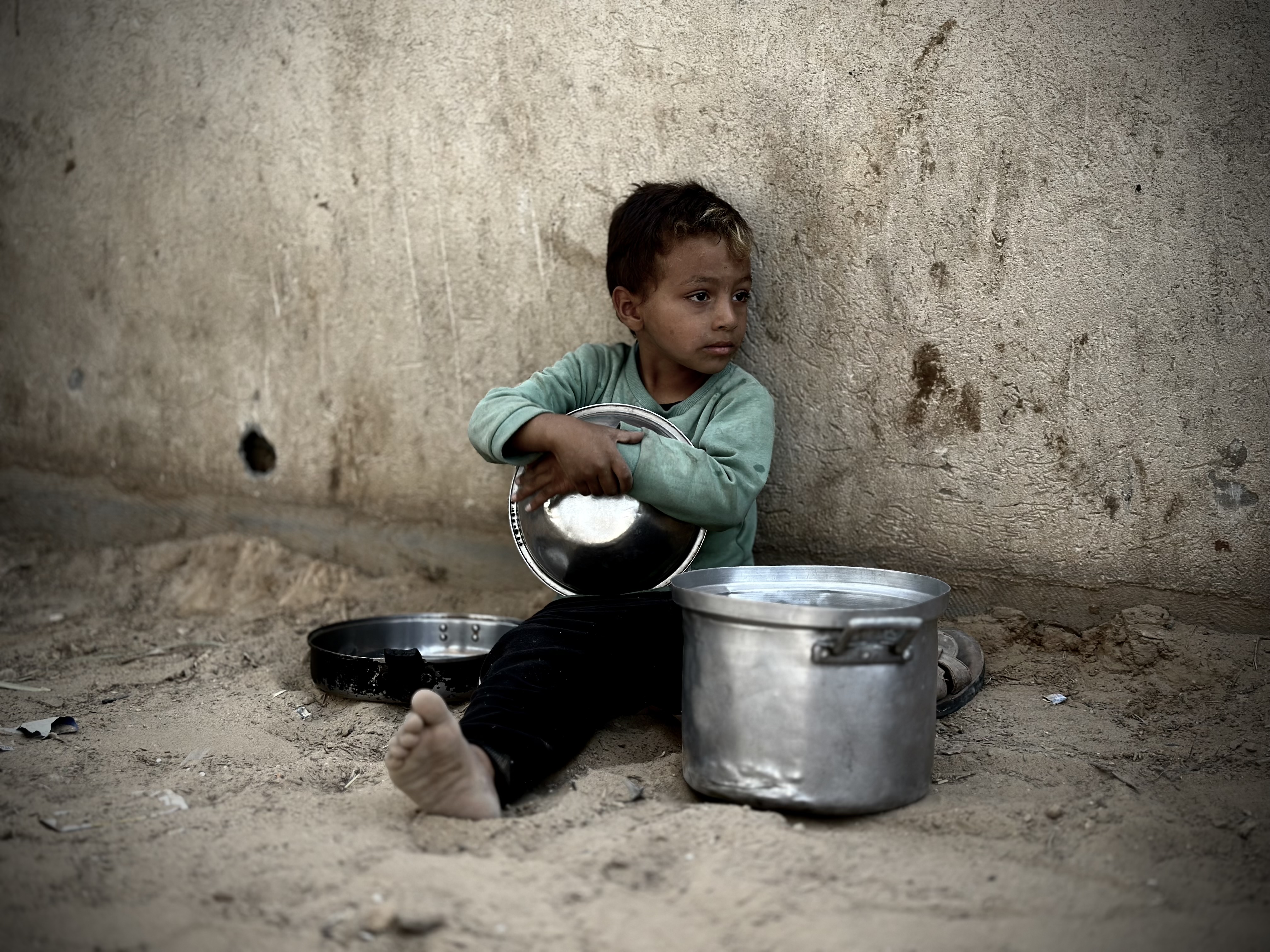 Palestinian child is seen with a pot as he waits to receive the food distributed by charitable organizations