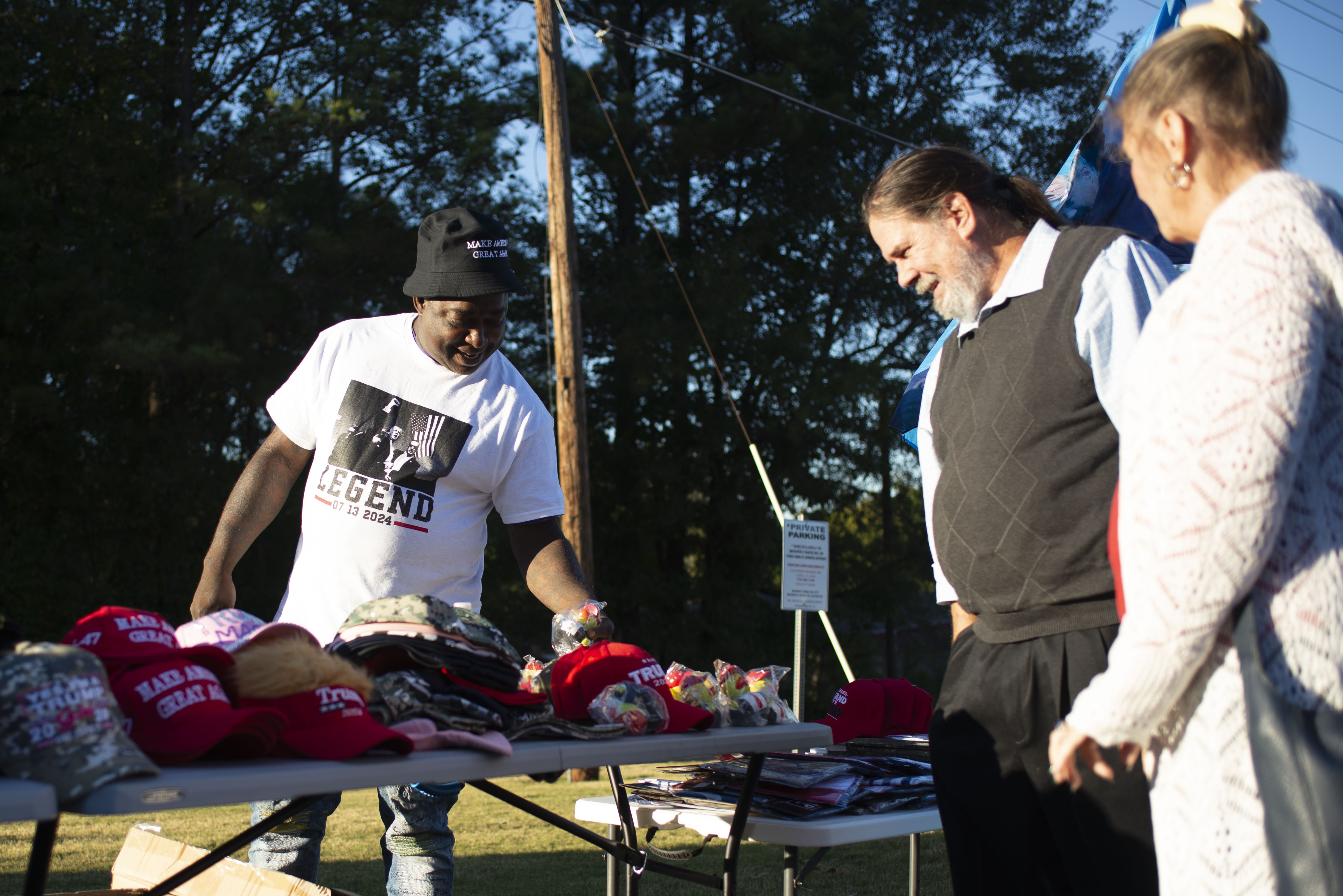 Attendees at a 'Believers for Trump' event look at Trump hats