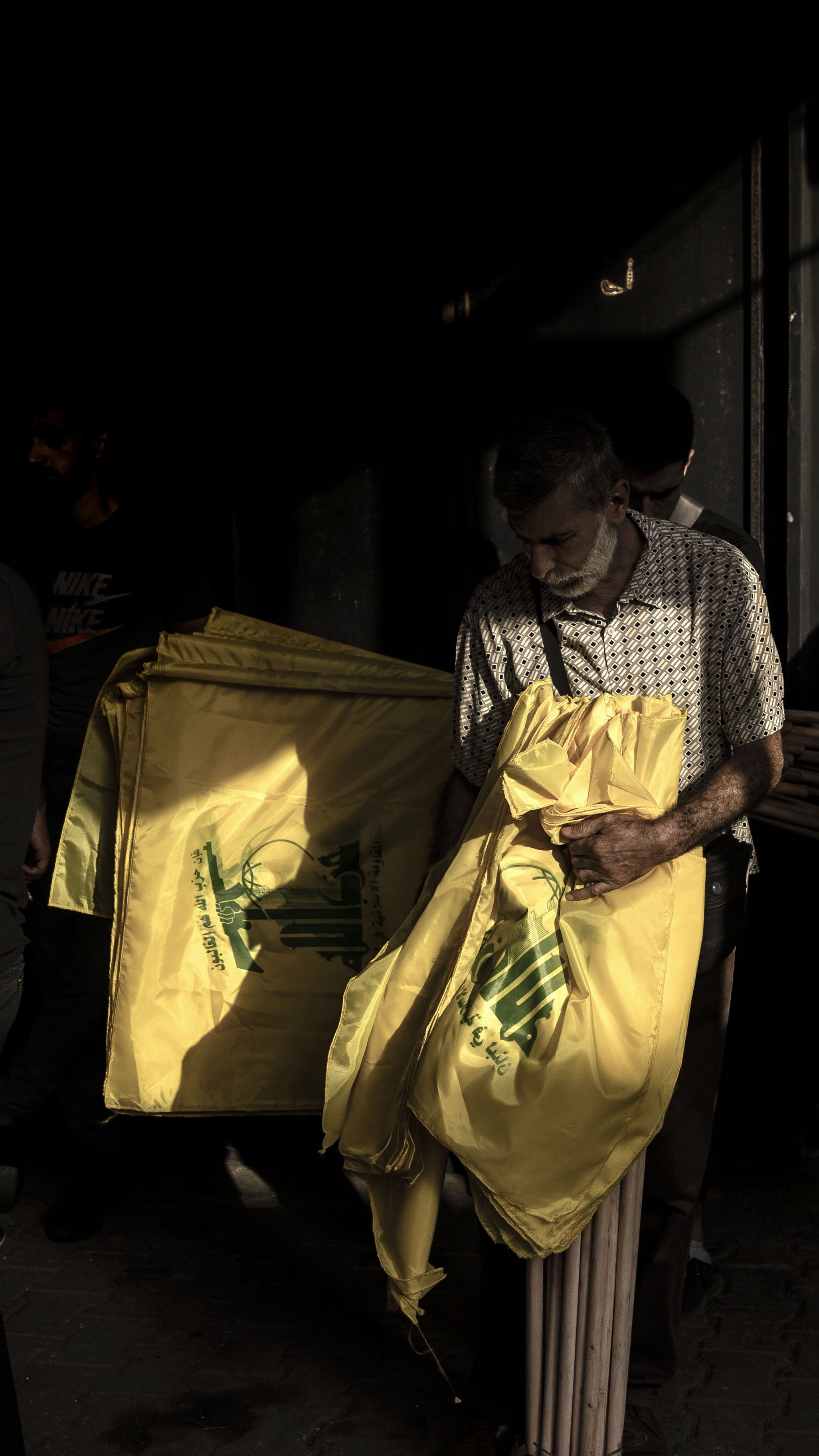 Hezbollah supporters hold flags to distribute among mourners at the funeral of a fighter killed by the Israeli army in Lebanon's south. The funeral was held in Dahiyeh on October 23, 2023 [Manu Brabo/Getty Images]