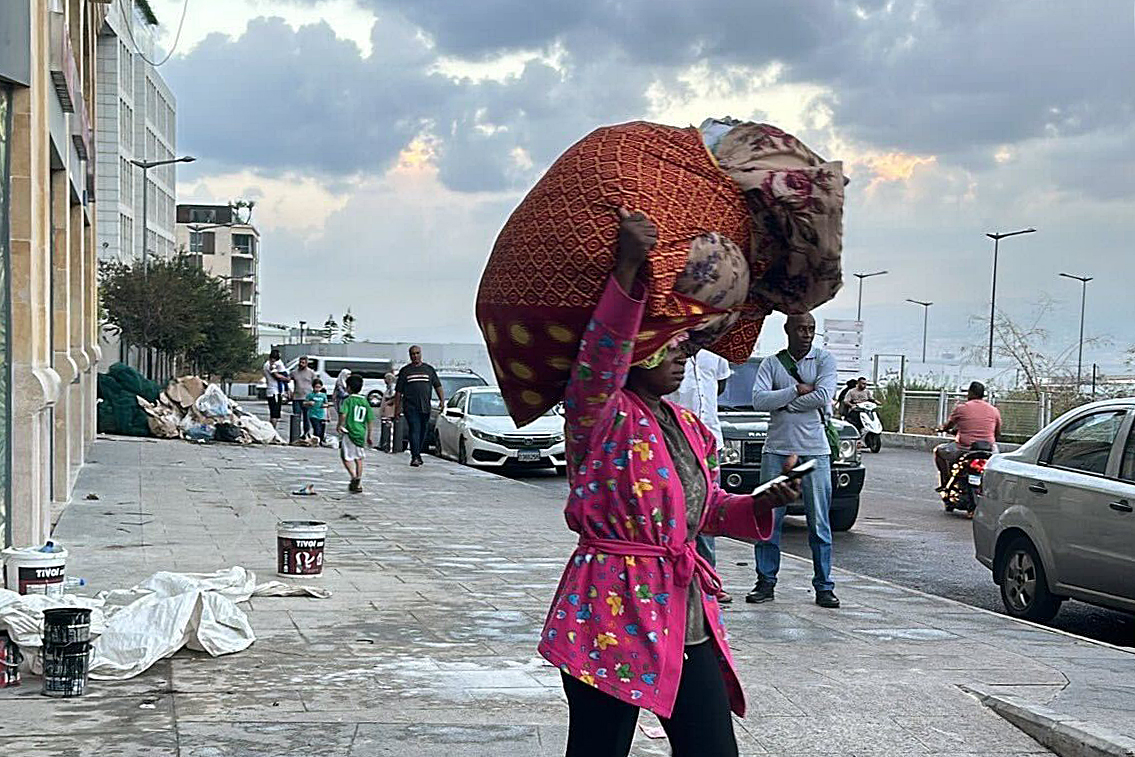 A migrant woman carrying her belongings in Beirut in the midst of Israel's war on the country