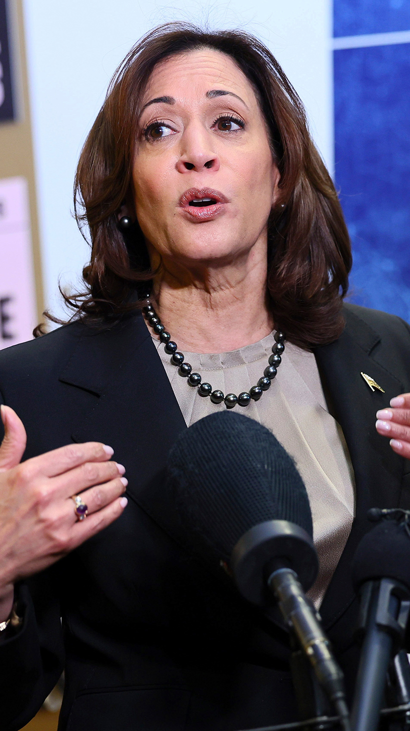 Kamala Harris speaks at a podium. Behind her is a wall that features posters about "reproductive freedom."