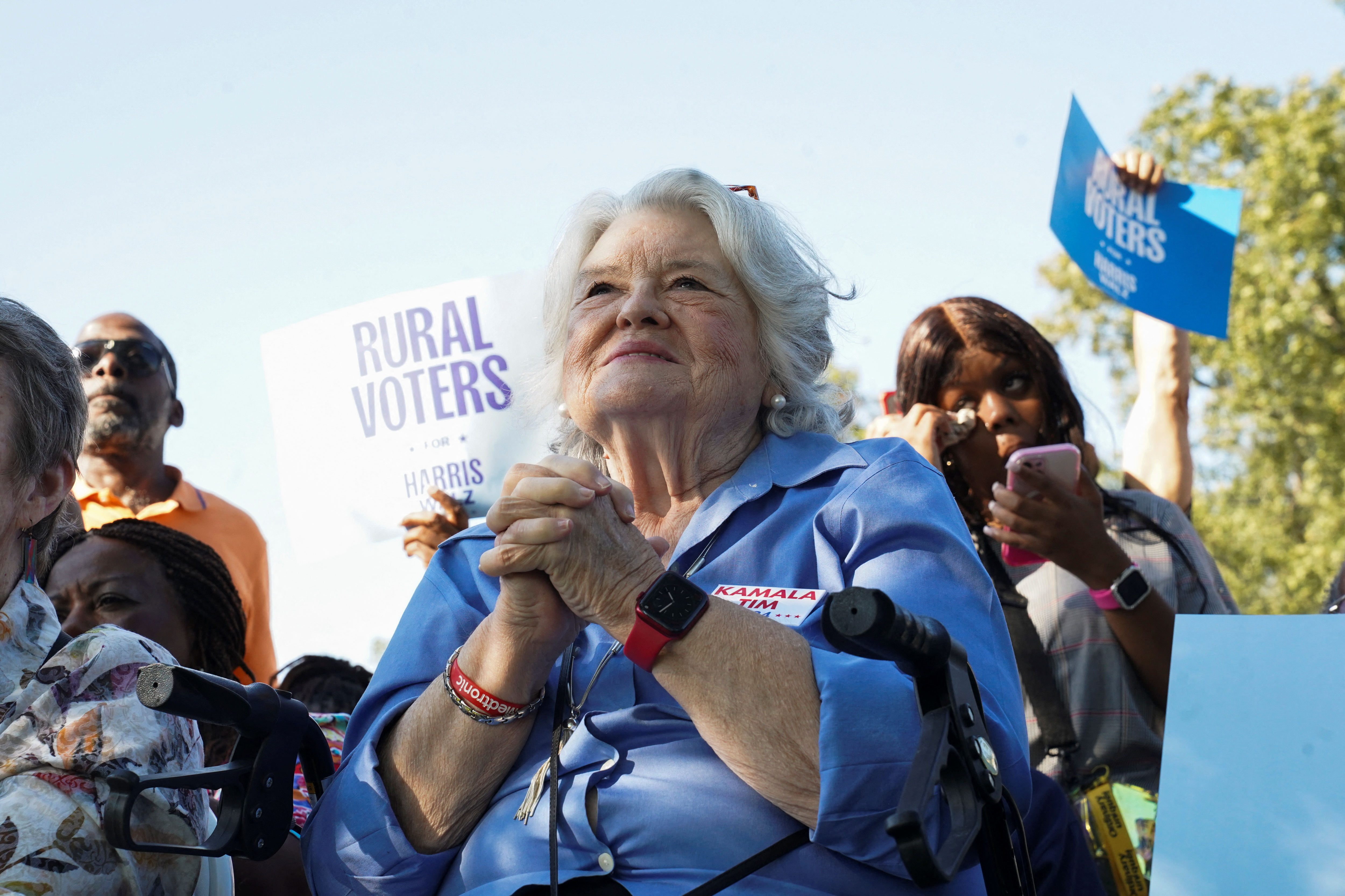A Harris supporter in Peach County clasps her hands together at an outdoor event.