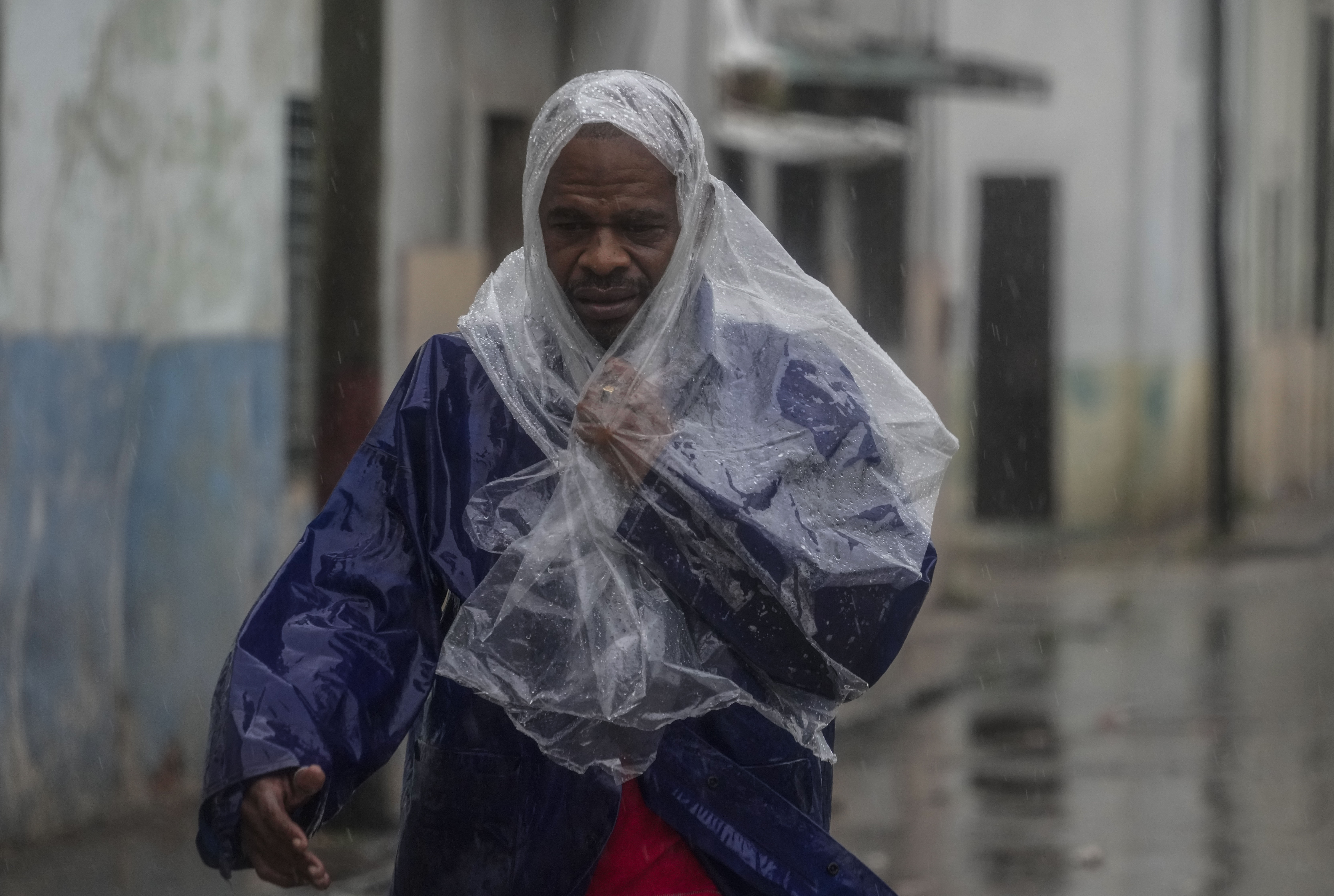 A person in a plastic poncho walks through the rain