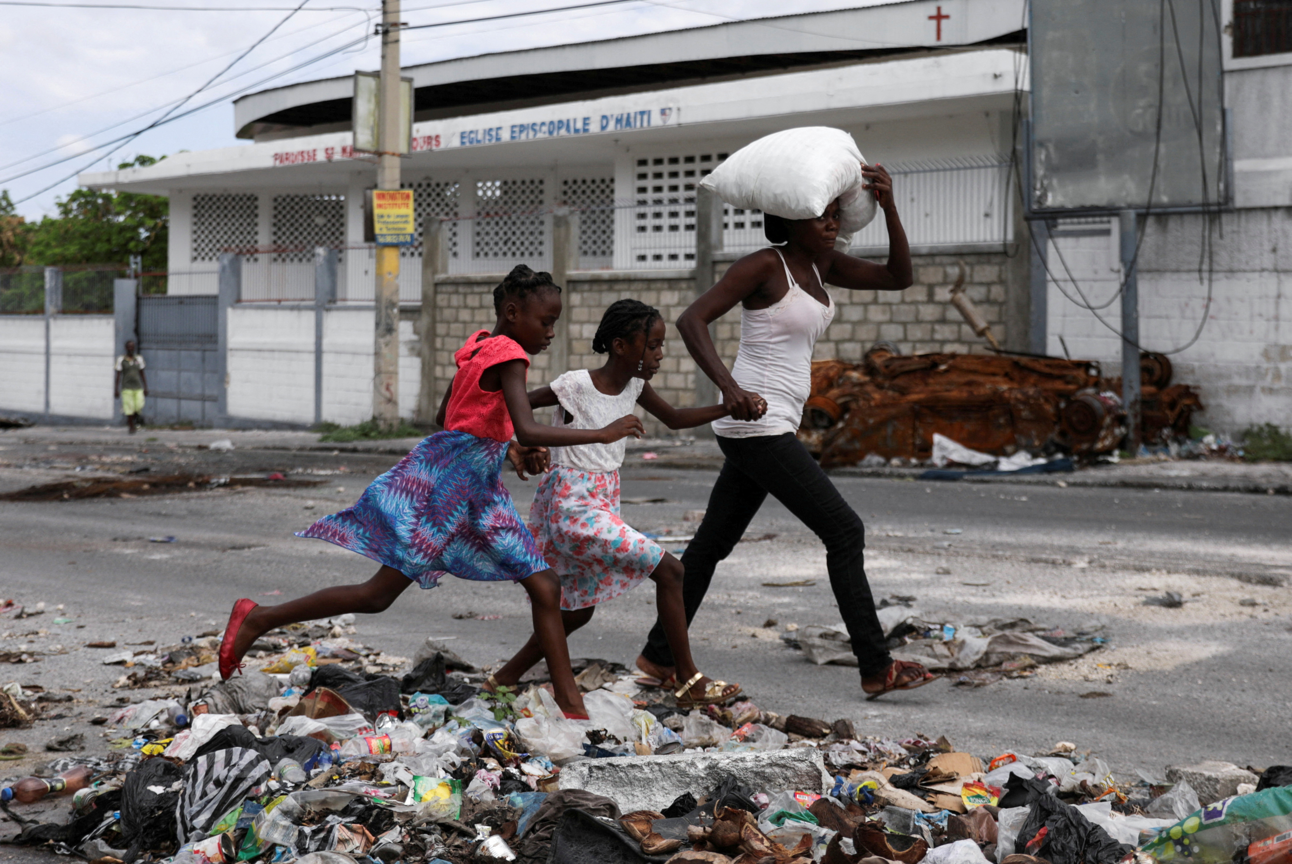 A woman with two children carries their belongings as residents of the Lower Delmas flee their homes due to gang violence, in Port-au-Prince, Haiti May 2